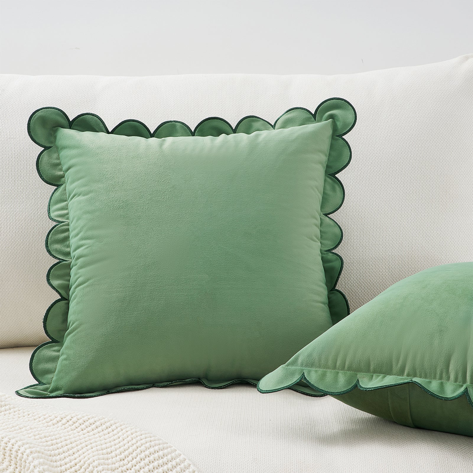 Green pillow with scalloped edge on a white background