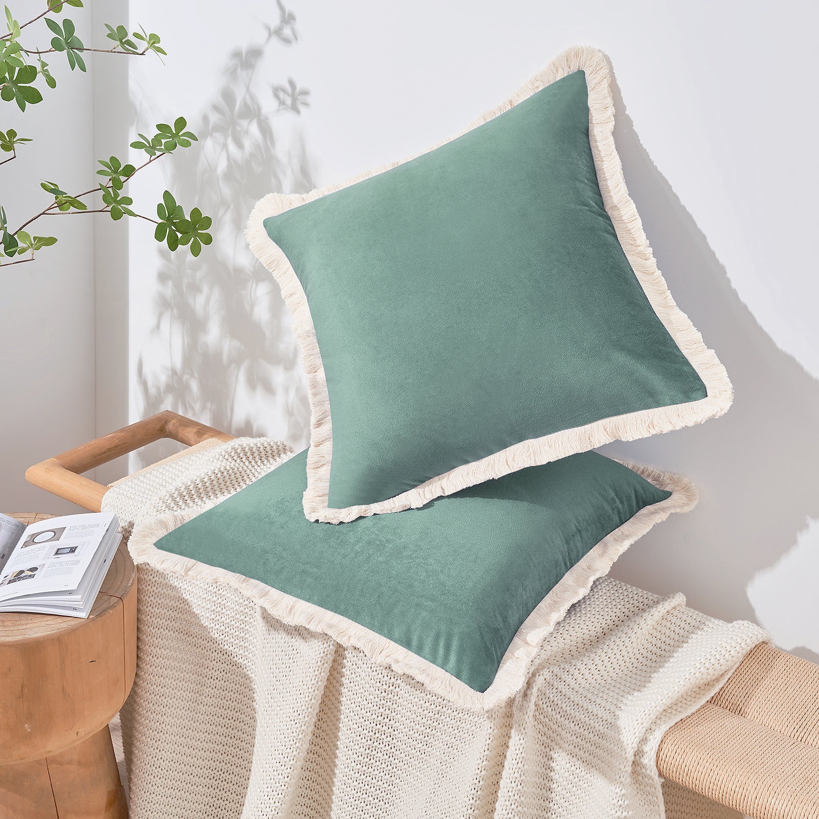 Two green pillows with white trim on a chair next to a wooden side table with a magazine.