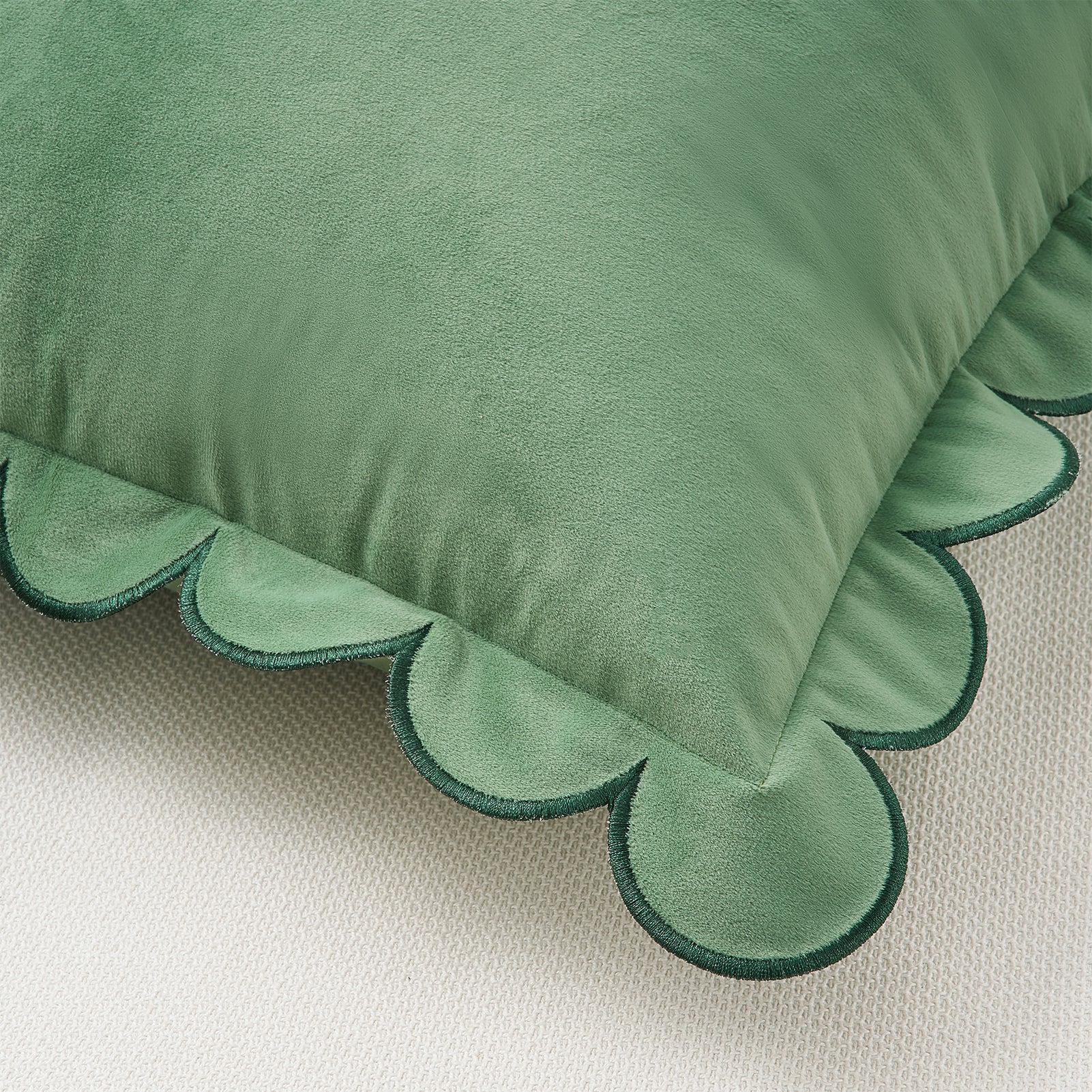 Green pillow with scalloped edge on a beige background