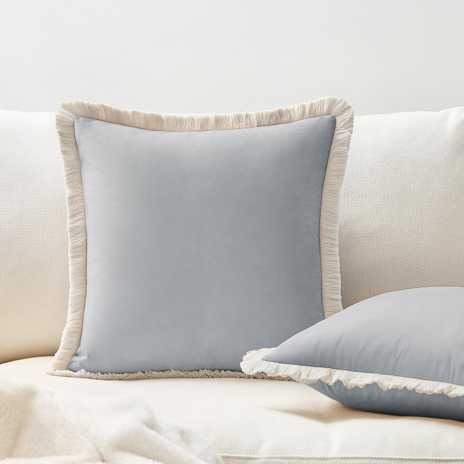 Gray pillows with frayed edges on a beige sofa