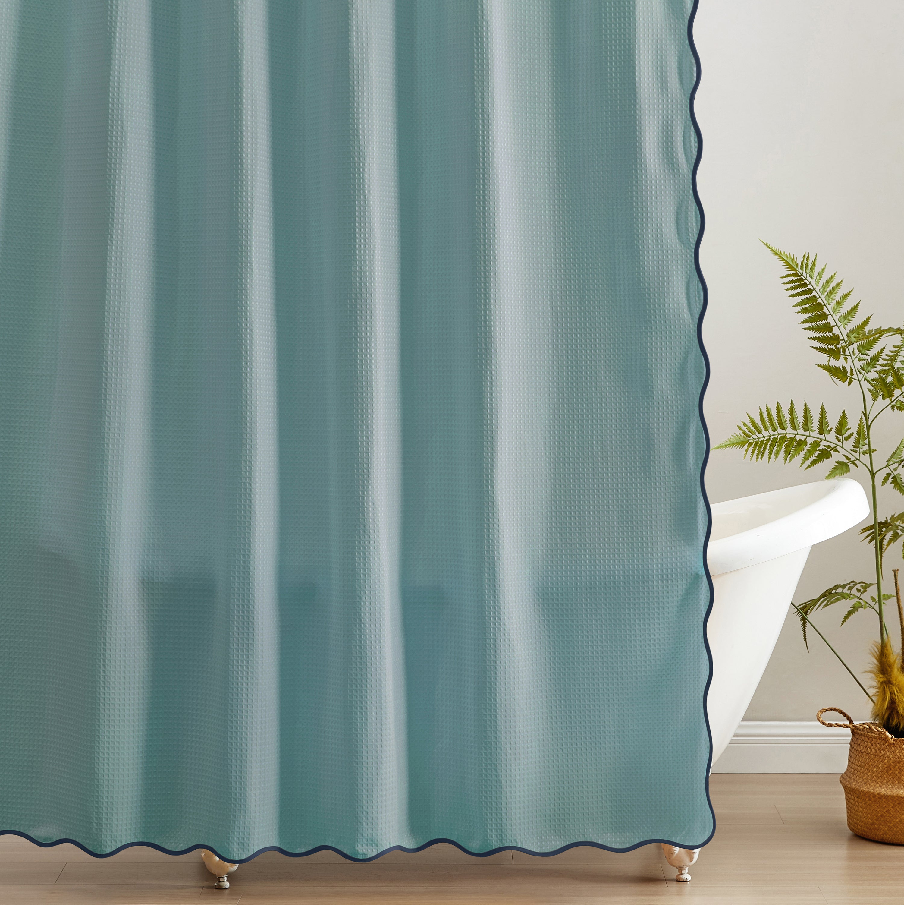 Teal curtain with scalloped edge in a room with a plant