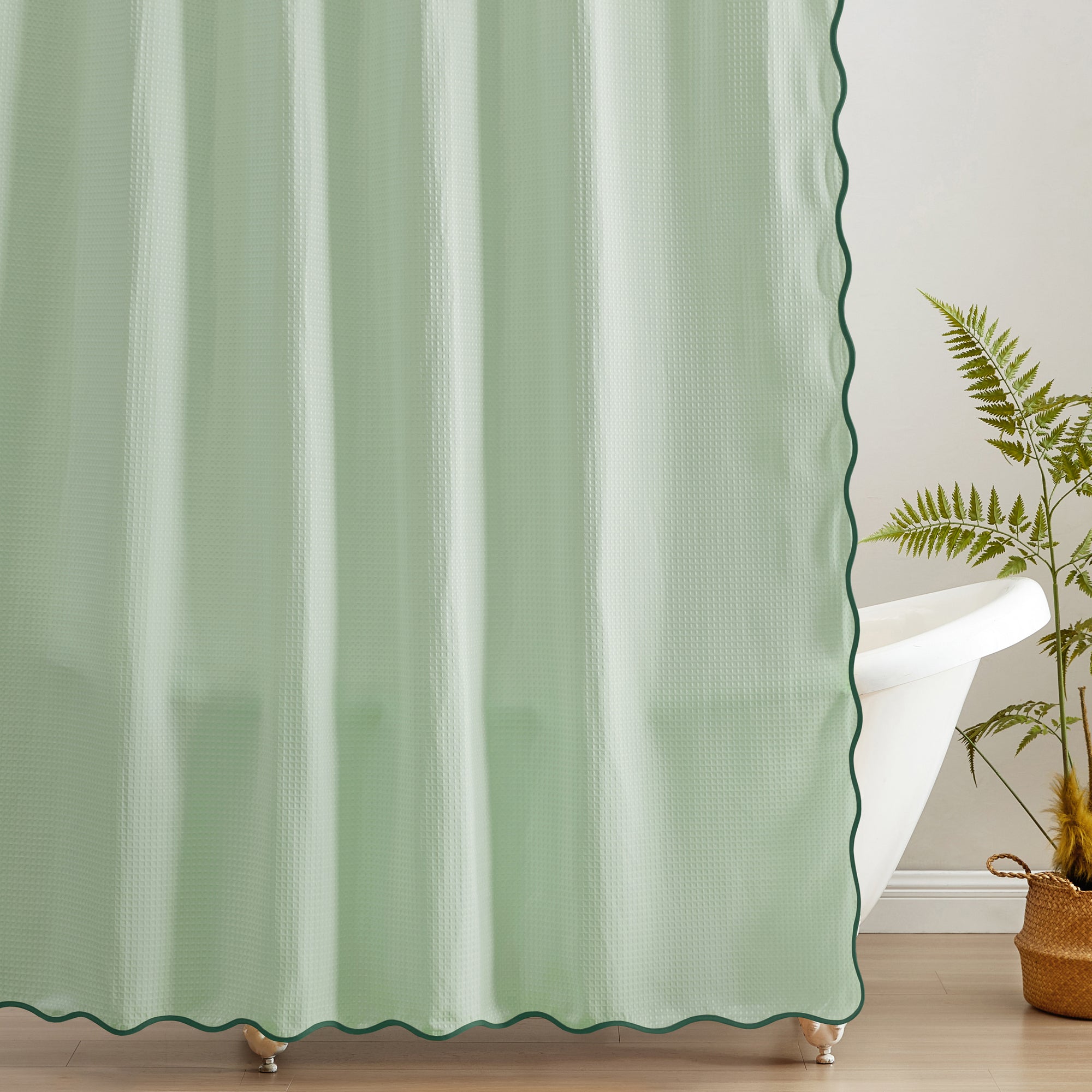 Green curtain with scalloped edge in a room with a plant