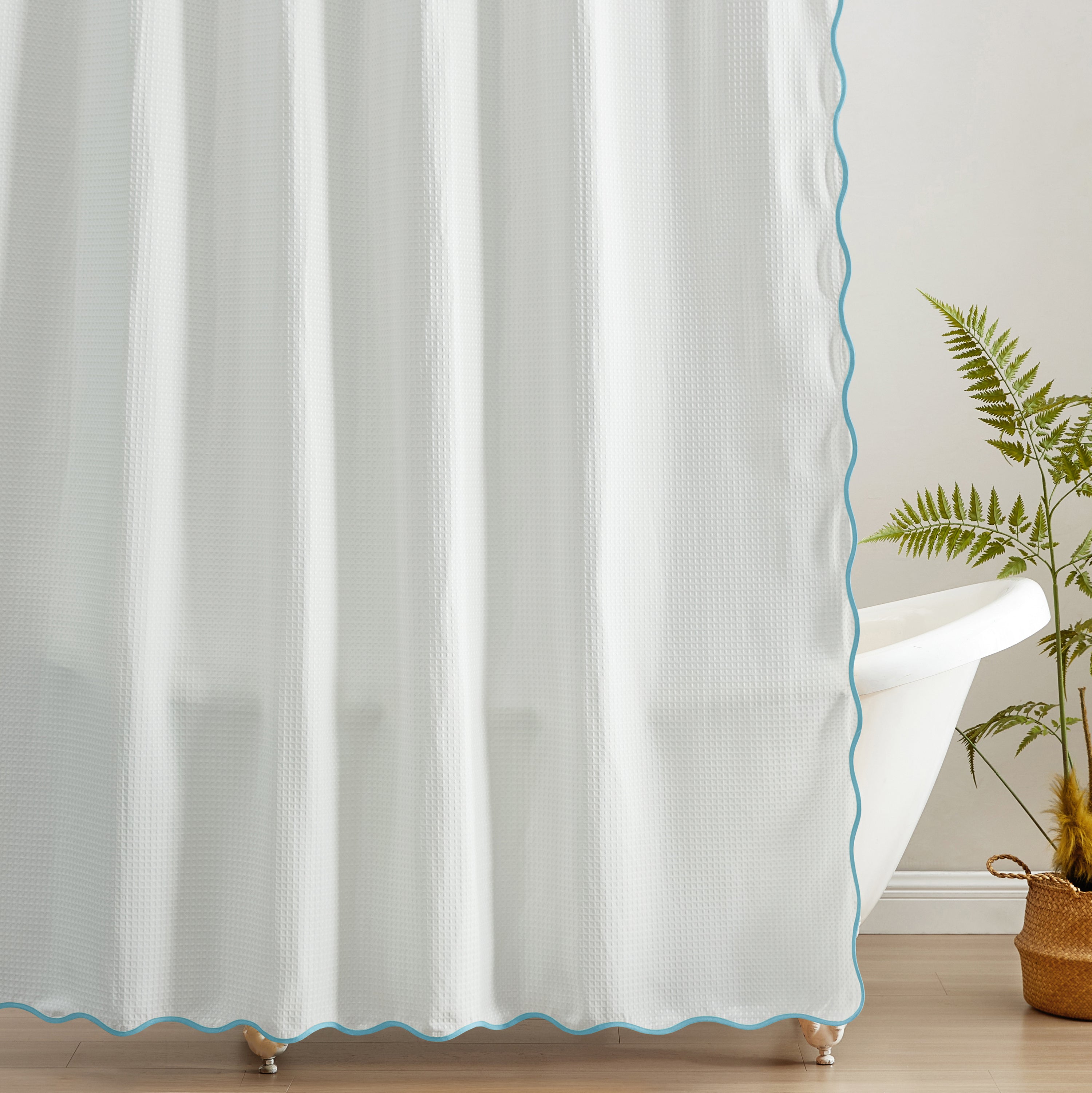 White curtain with blue trim in a room with a plant