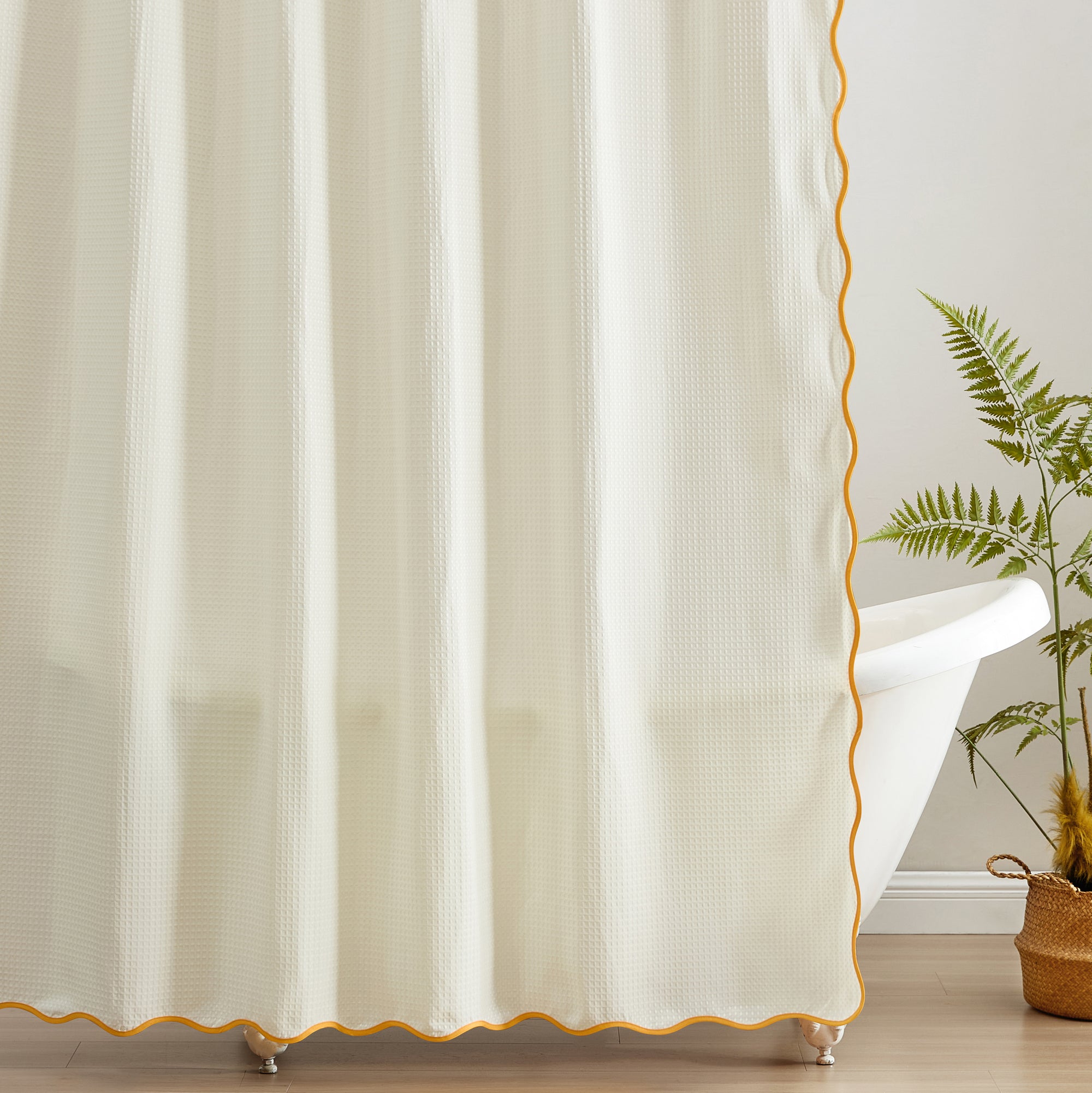 White curtain with gold trim in a room with a plant