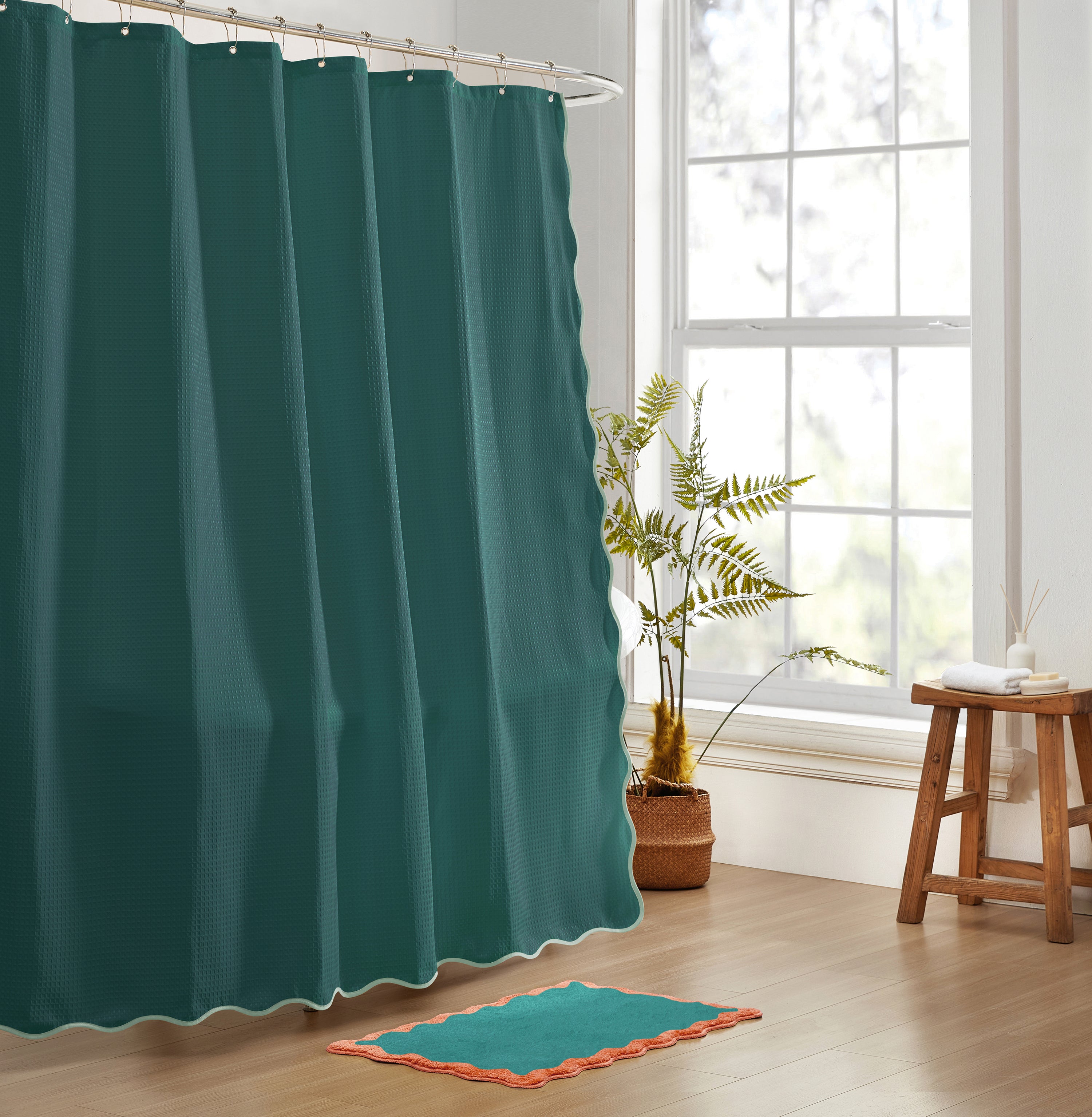 Teal shower curtain in a bathroom with a plant and stool.