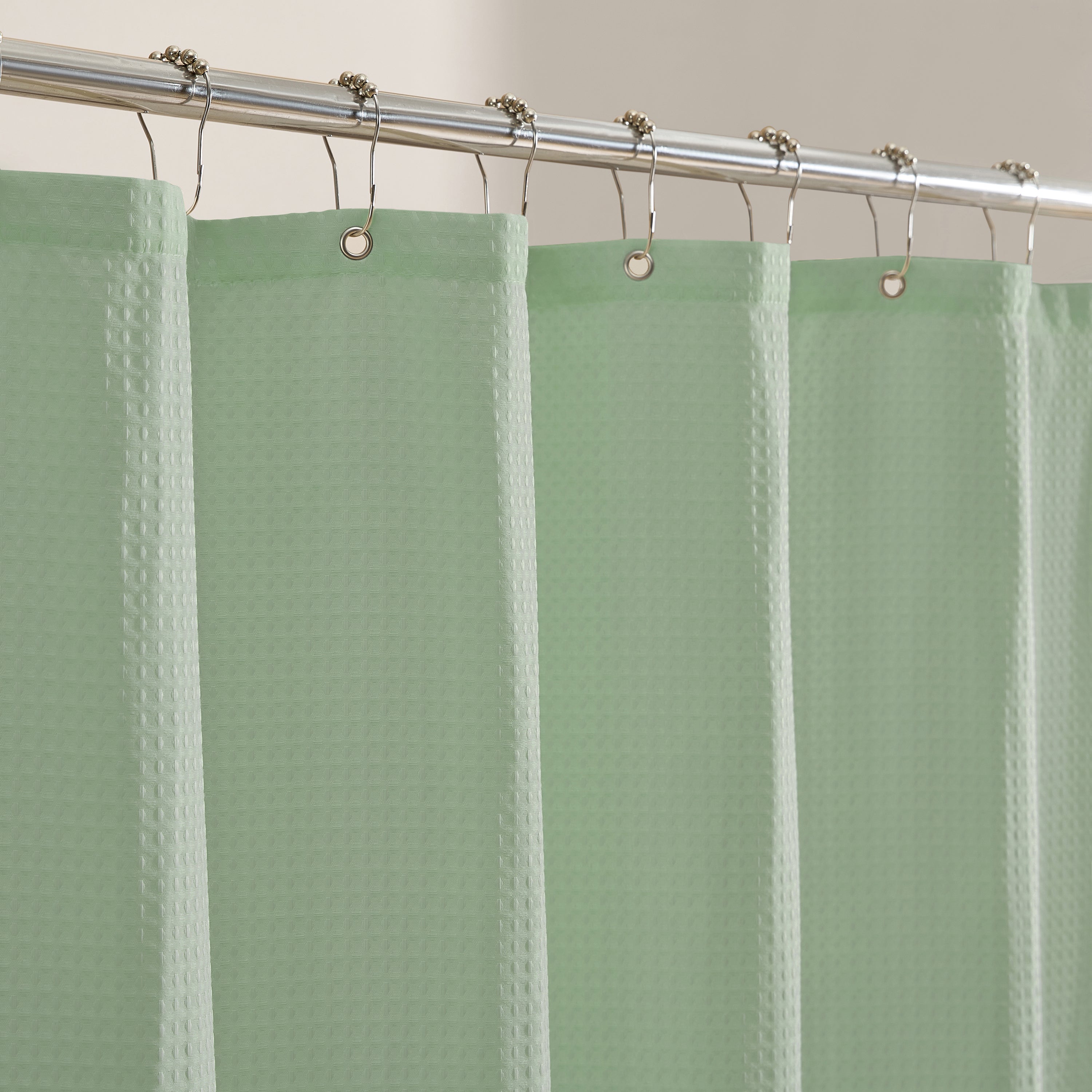 Green shower curtain with a textured pattern on a silver rod.