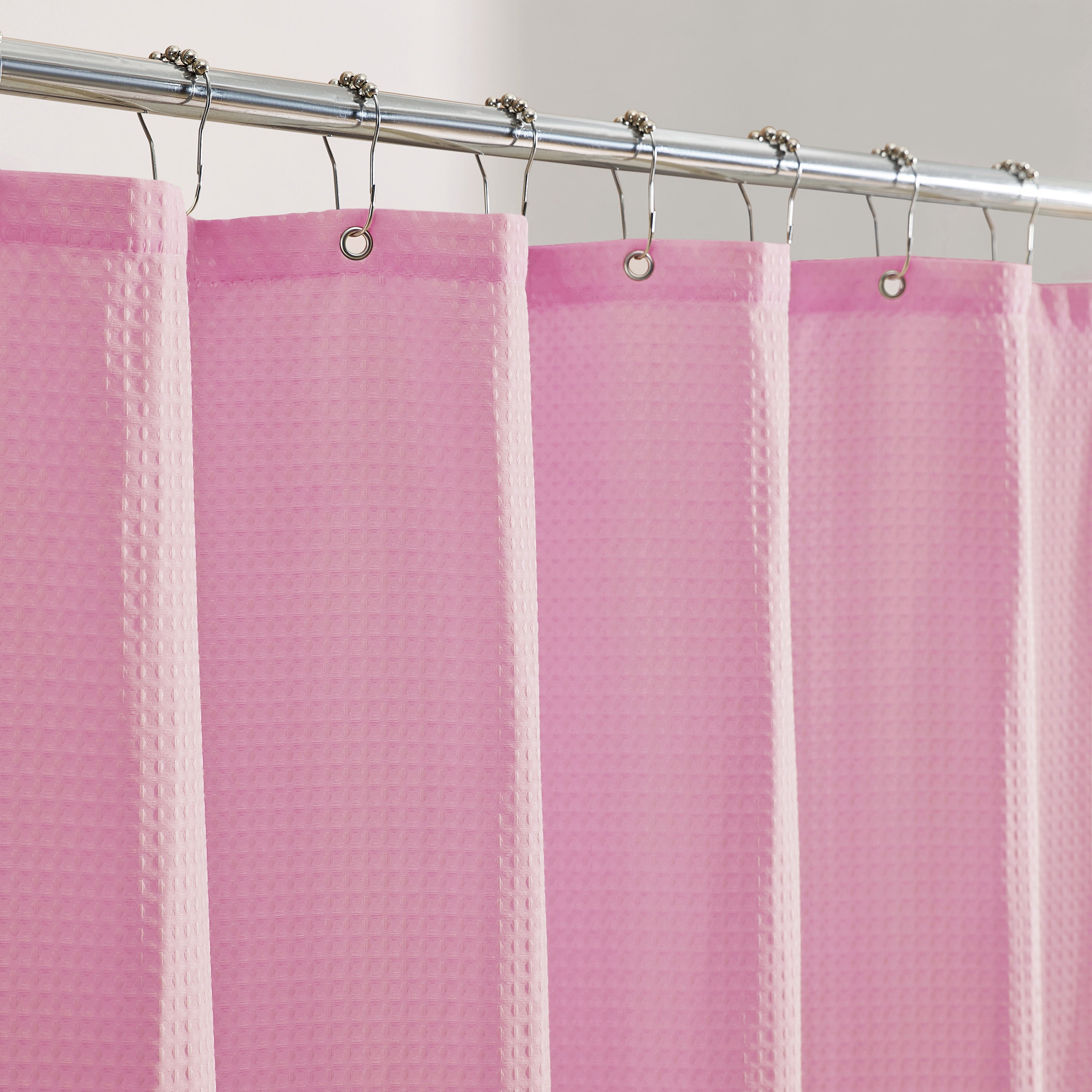 Pink shower curtain with a textured pattern on a silver curtain rod.