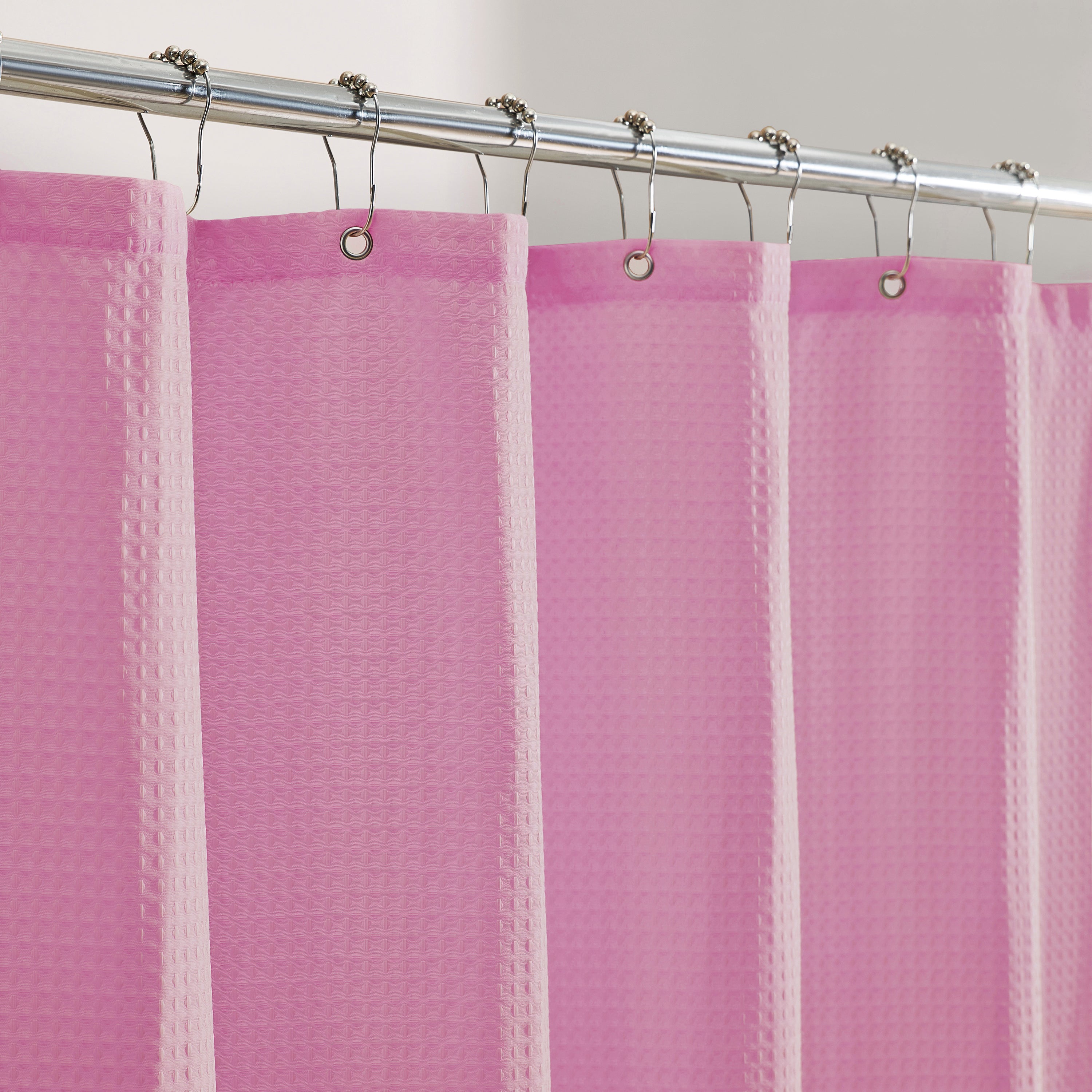 Pink shower curtain with a textured pattern on a silver curtain rod.