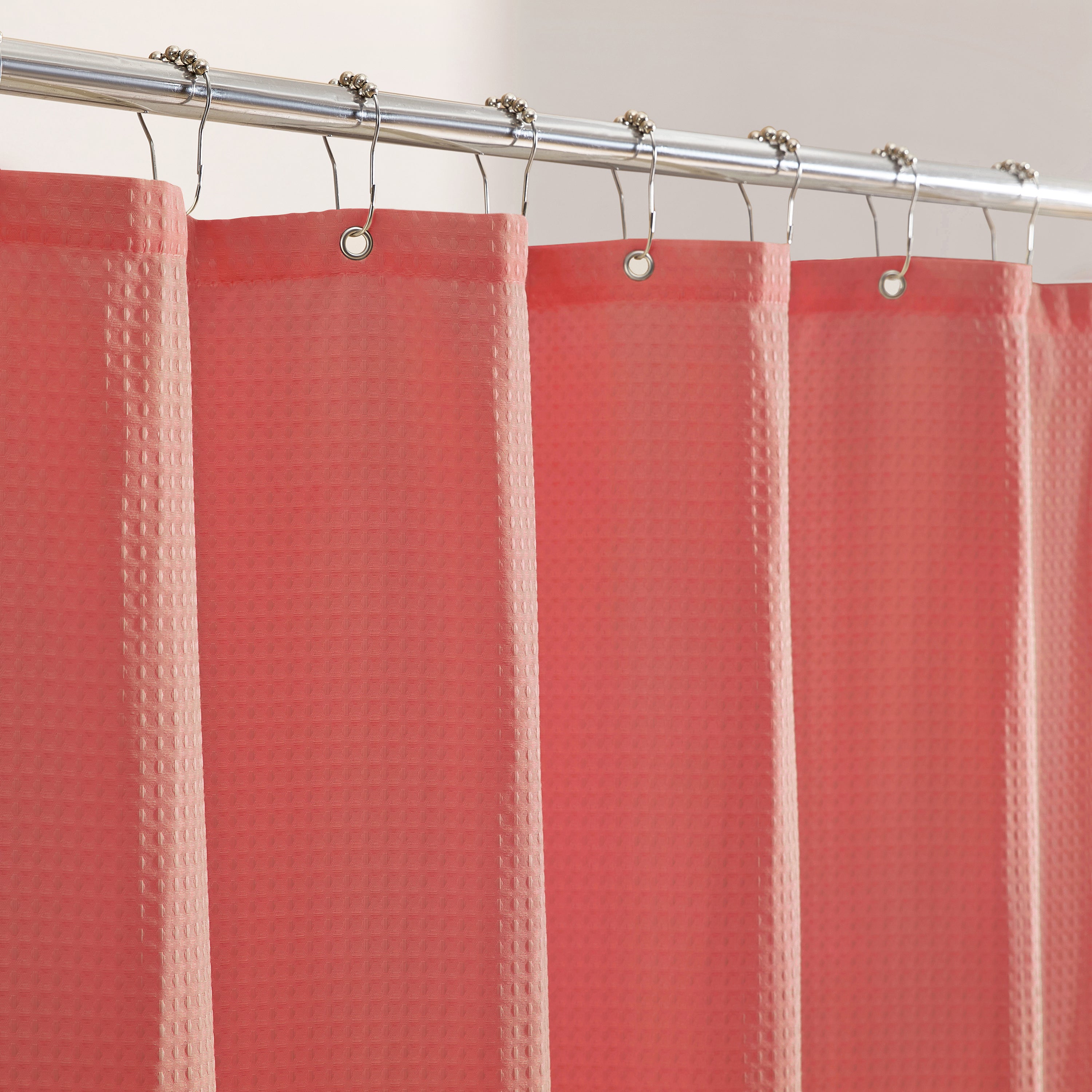 Red textured shower curtain with silver hooks on a white background