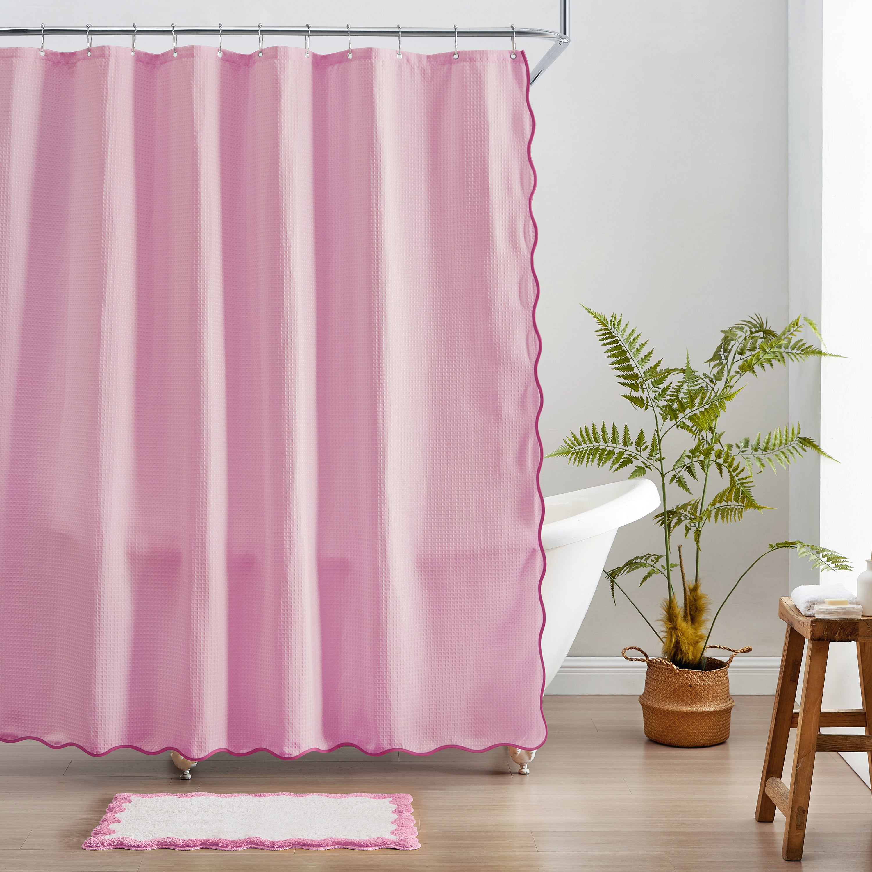 Pink striped shower curtain in a bathroom with a plant and stool.