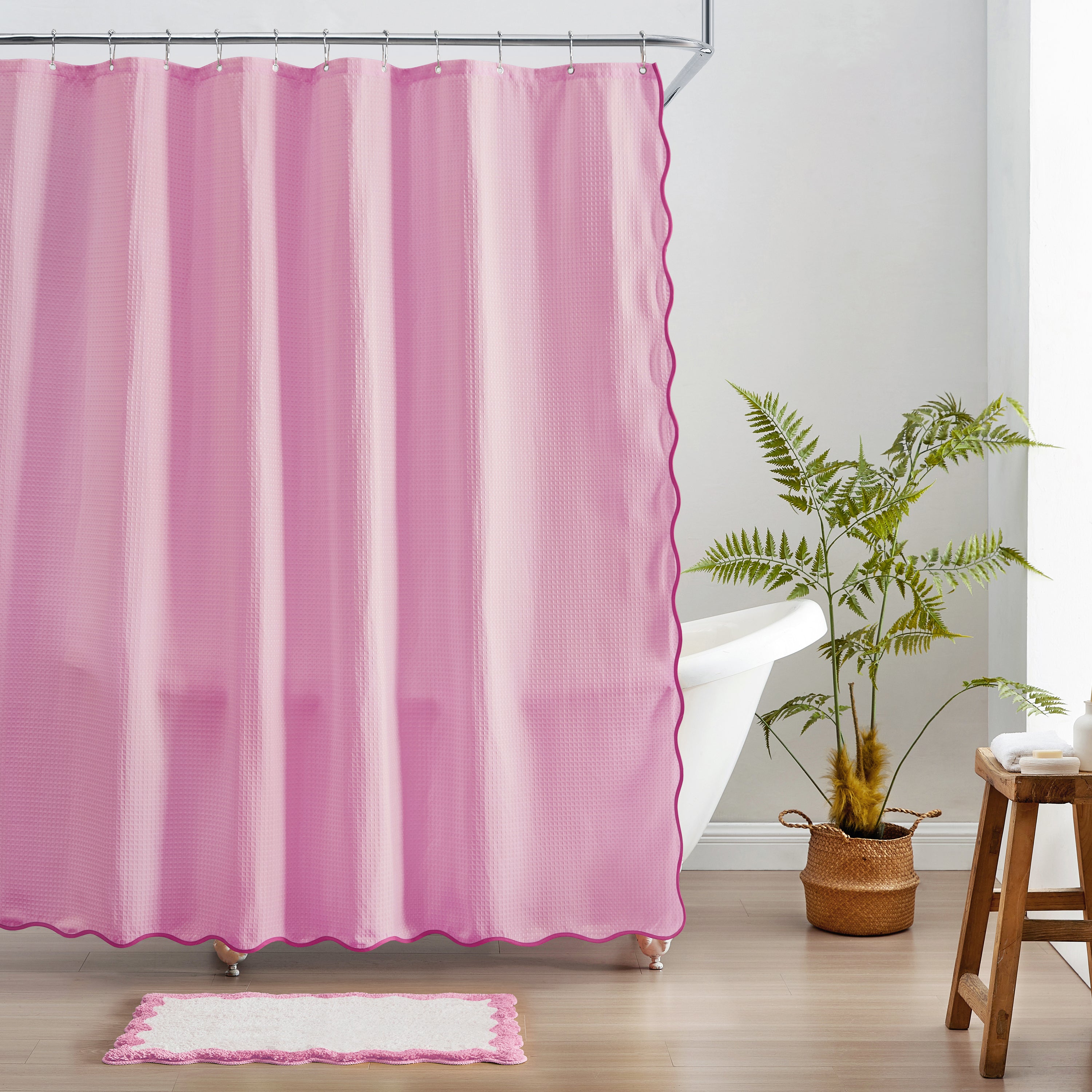 Pink shower curtain with a plant and stool in a bathroom setting