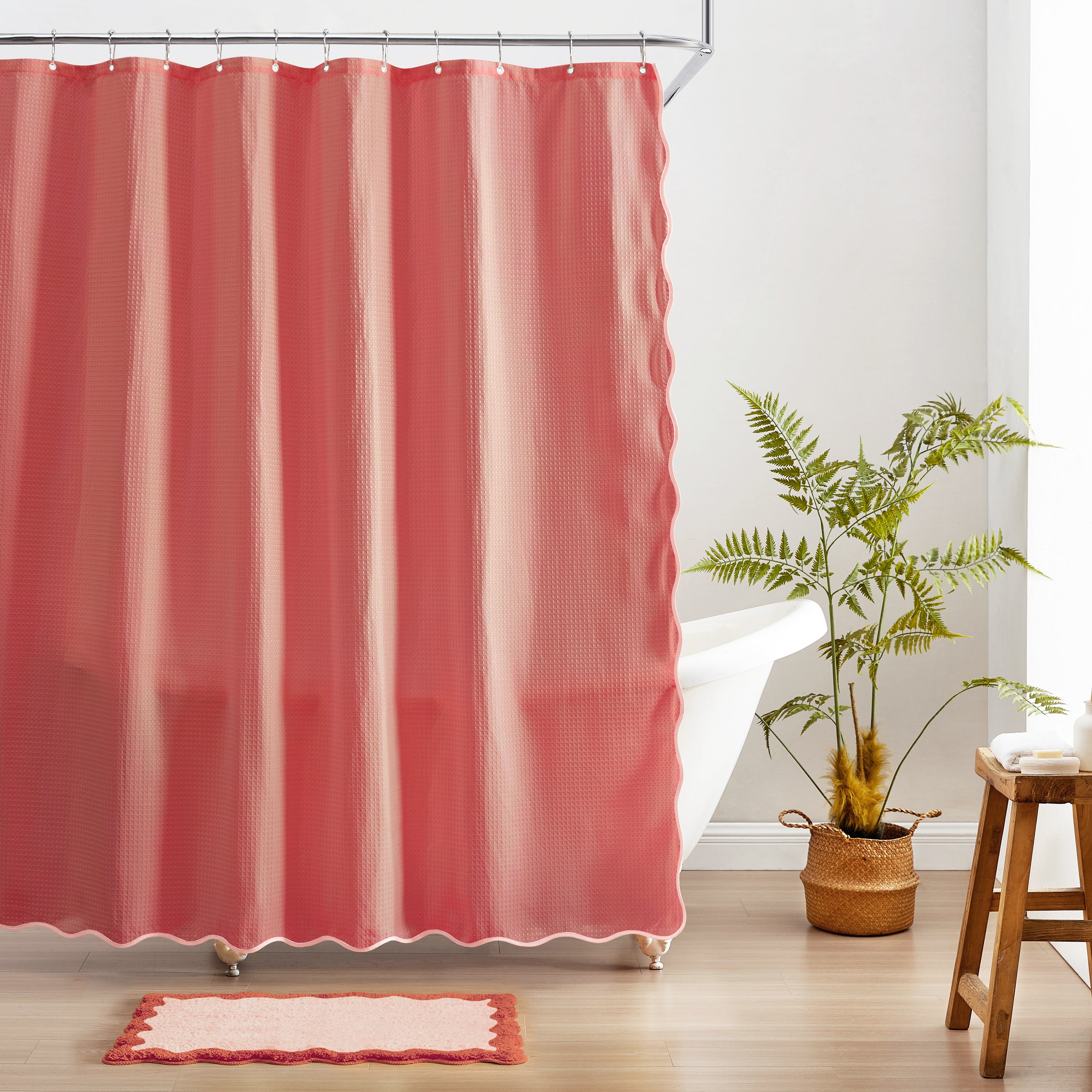Red shower curtain in a bathroom with a plant and stool.