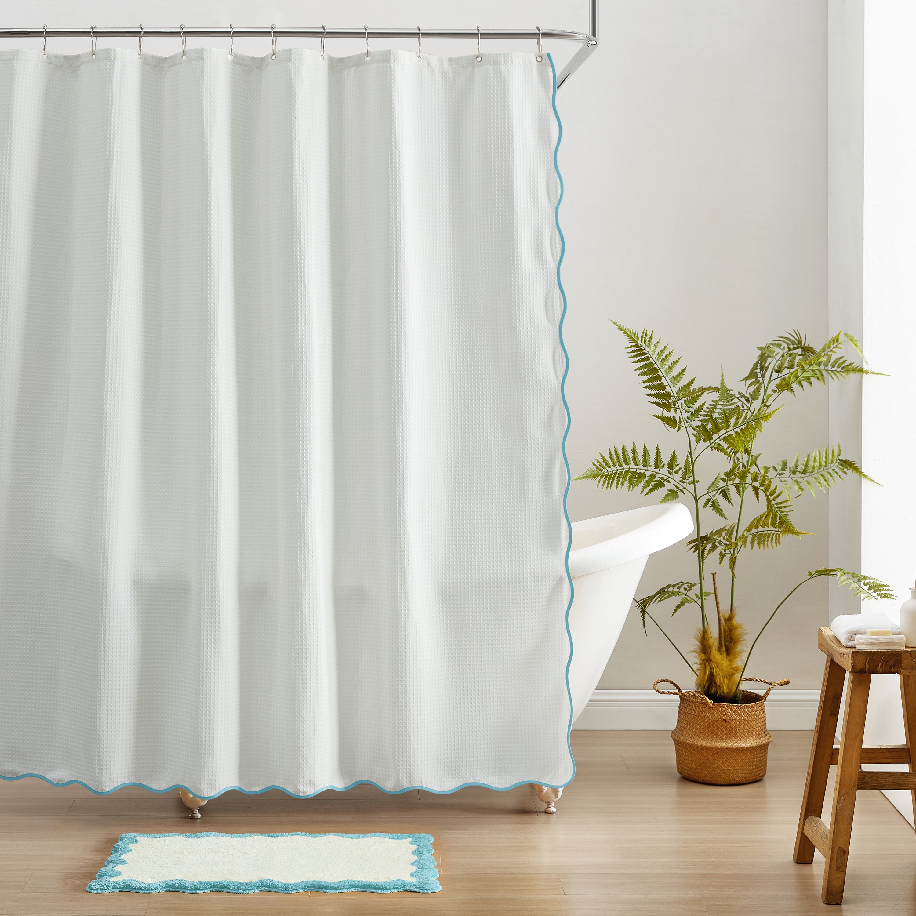 White shower curtain with blue trim in a bathroom setting.