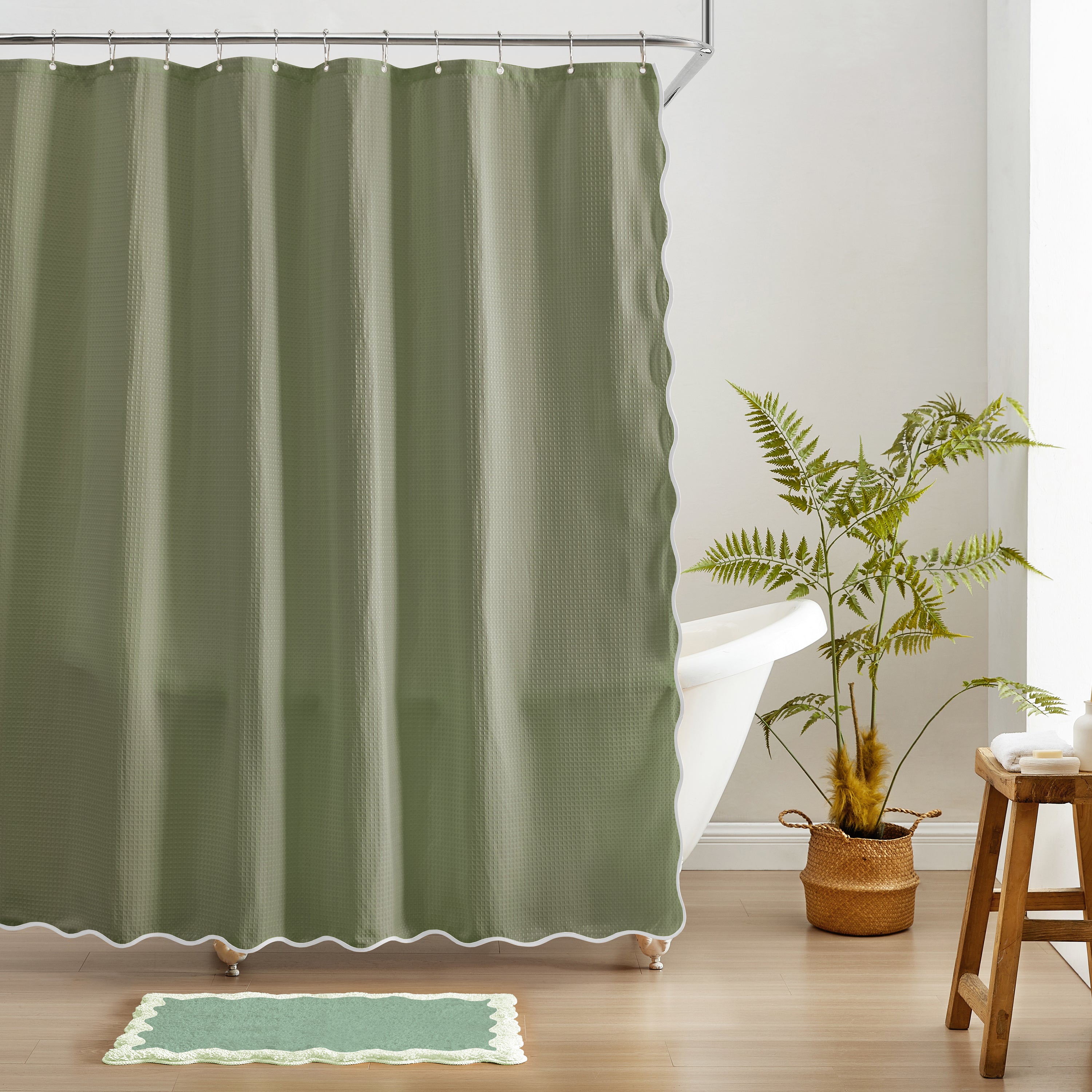Green shower curtain in a bathroom with a plant and stool.