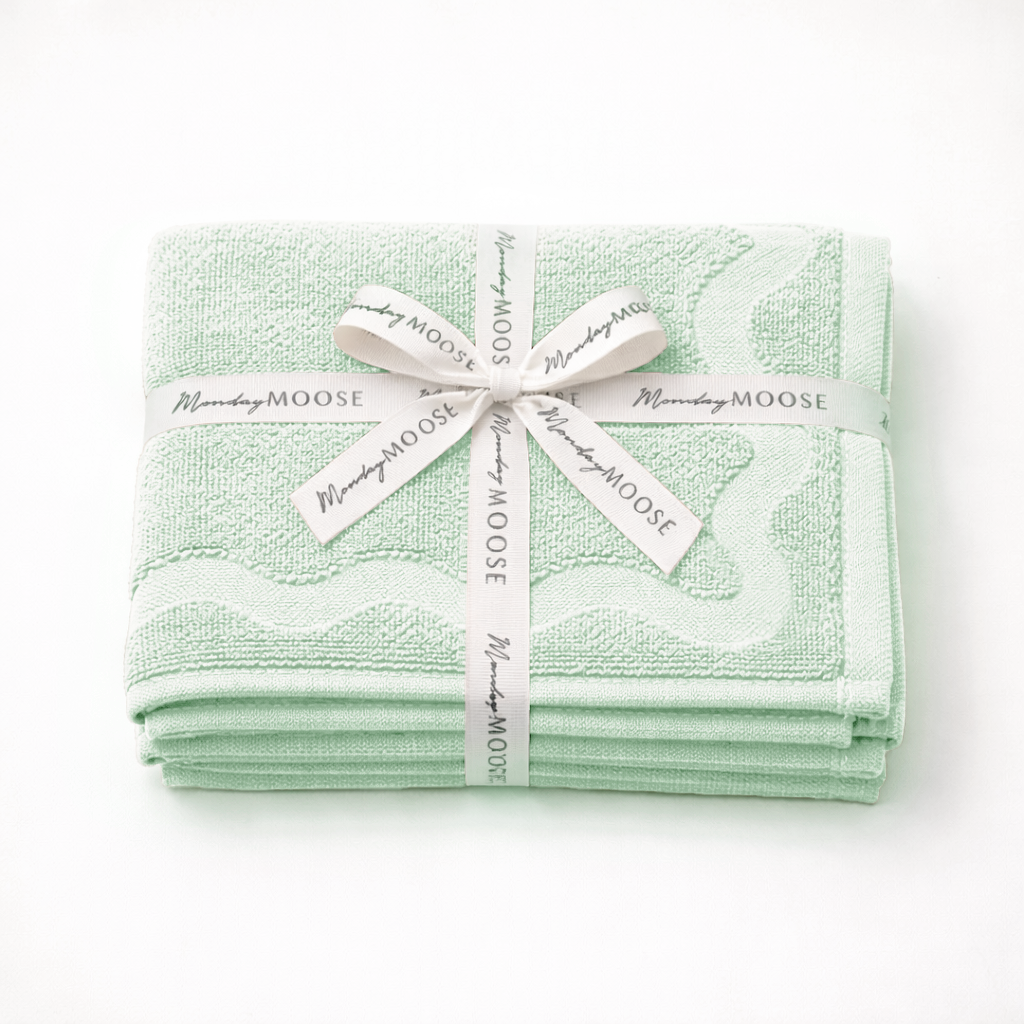 Set of green towels with a decorative ribbon on a white background