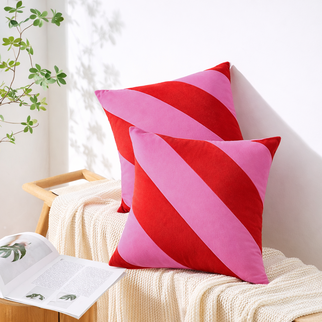 Pink and red striped cushions on a white surface with a plant in the background