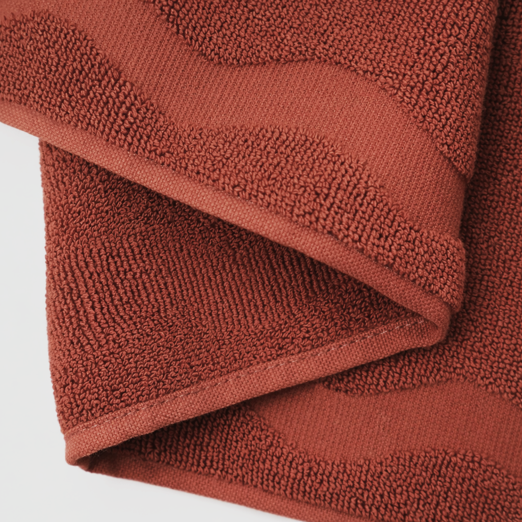 Folded terracotta-colored towel on a white background
