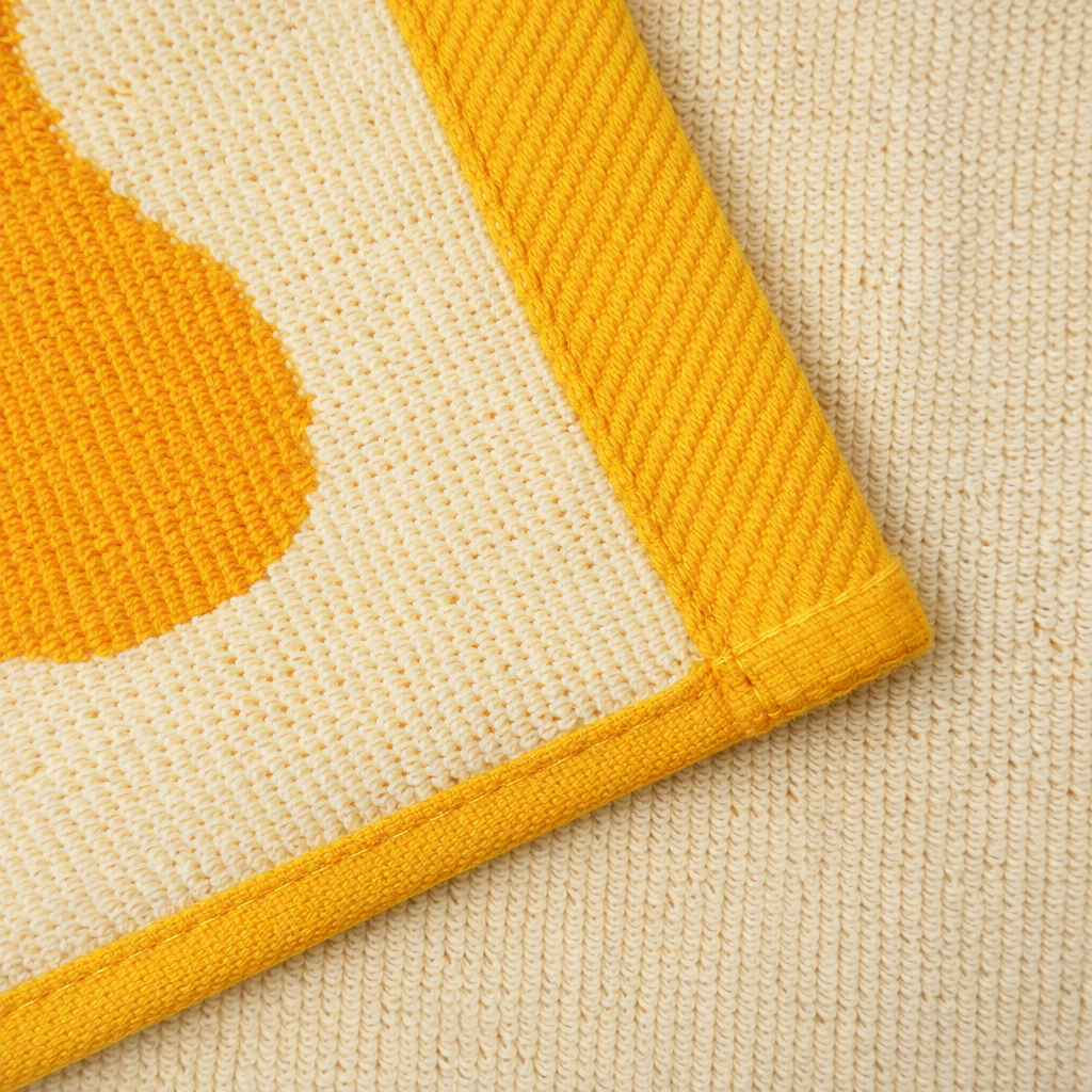 Close-up of a textured fabric with yellow and orange patterns on a beige background