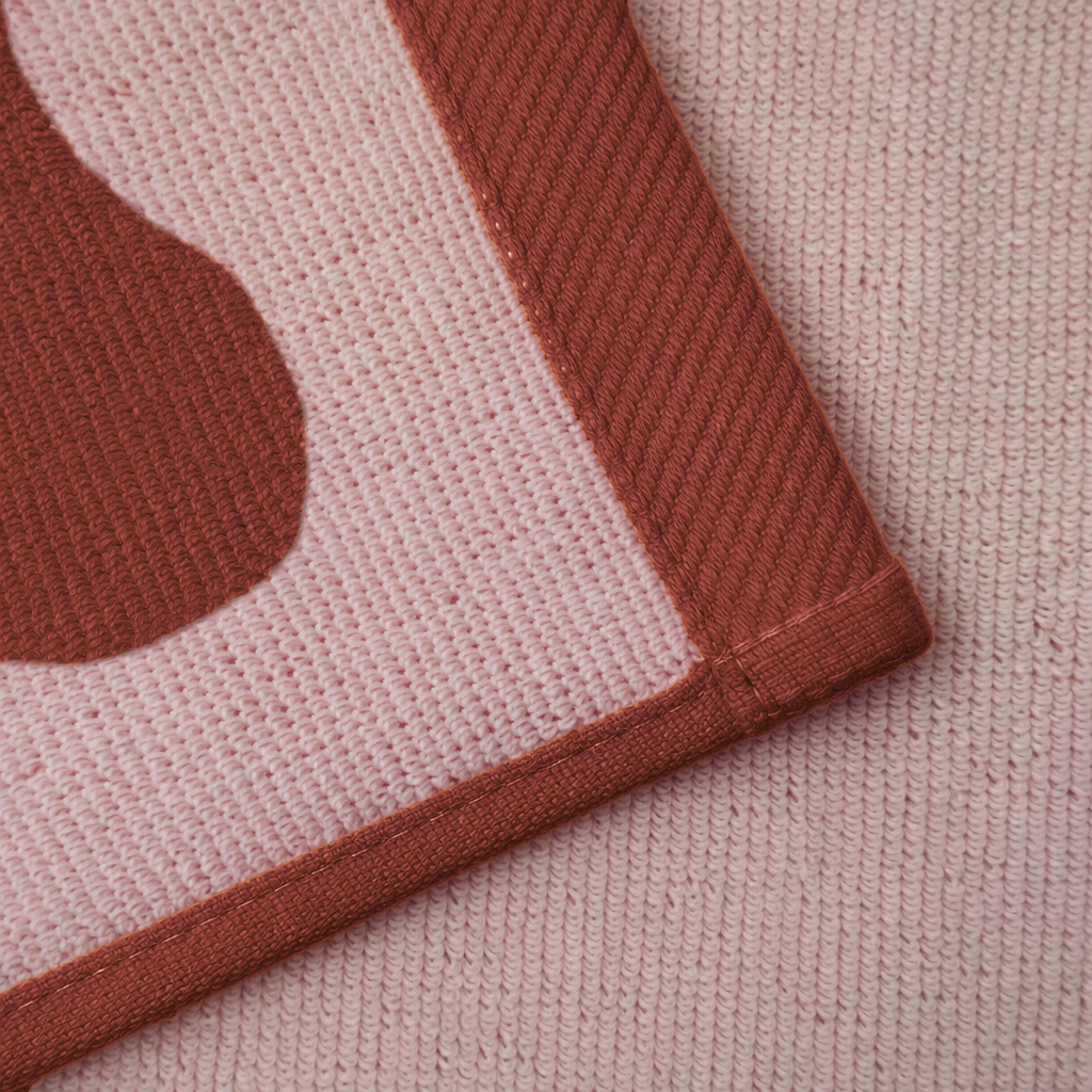 Close-up of a textured fabric with a geometric pattern on a pink background