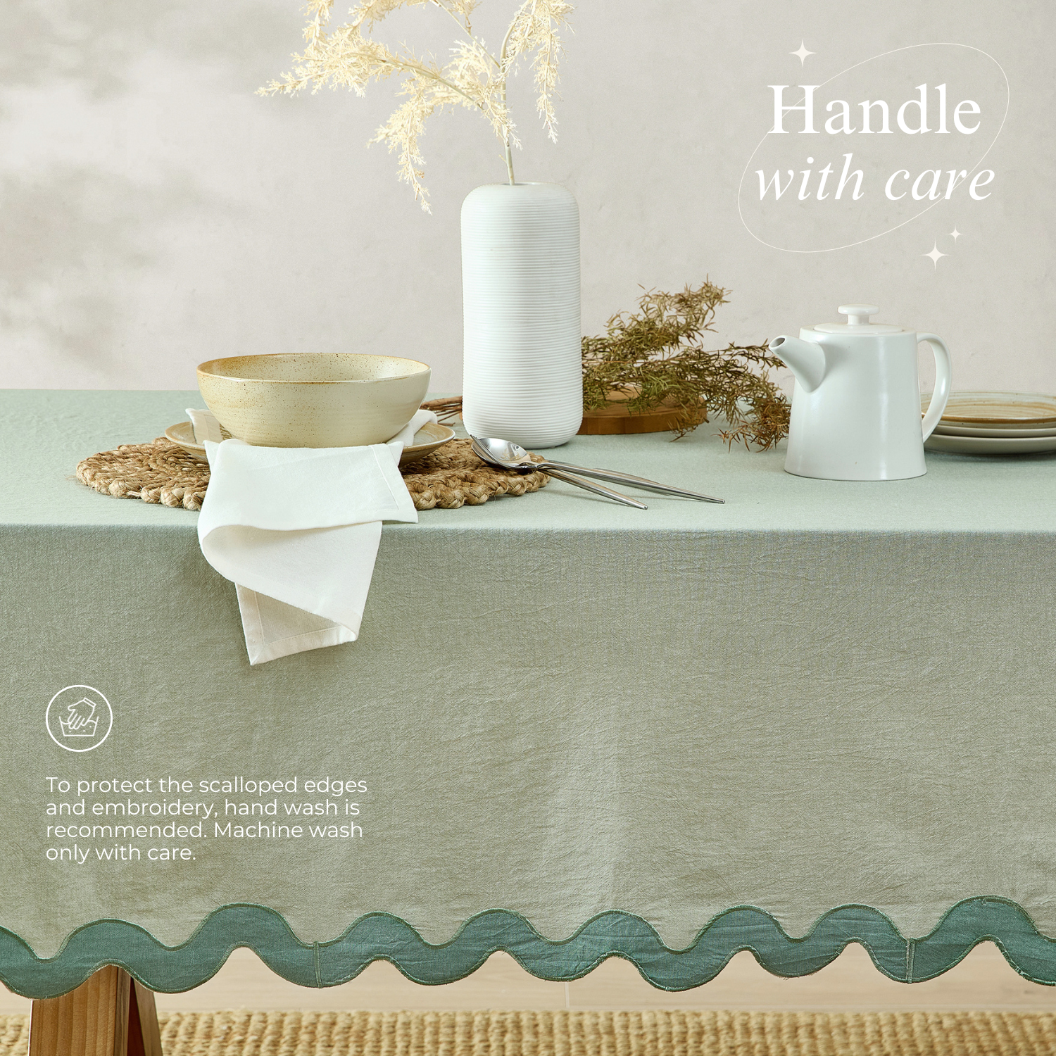 Table setting with a green tablecloth, white teapot, and decorative elements on a neutral background.