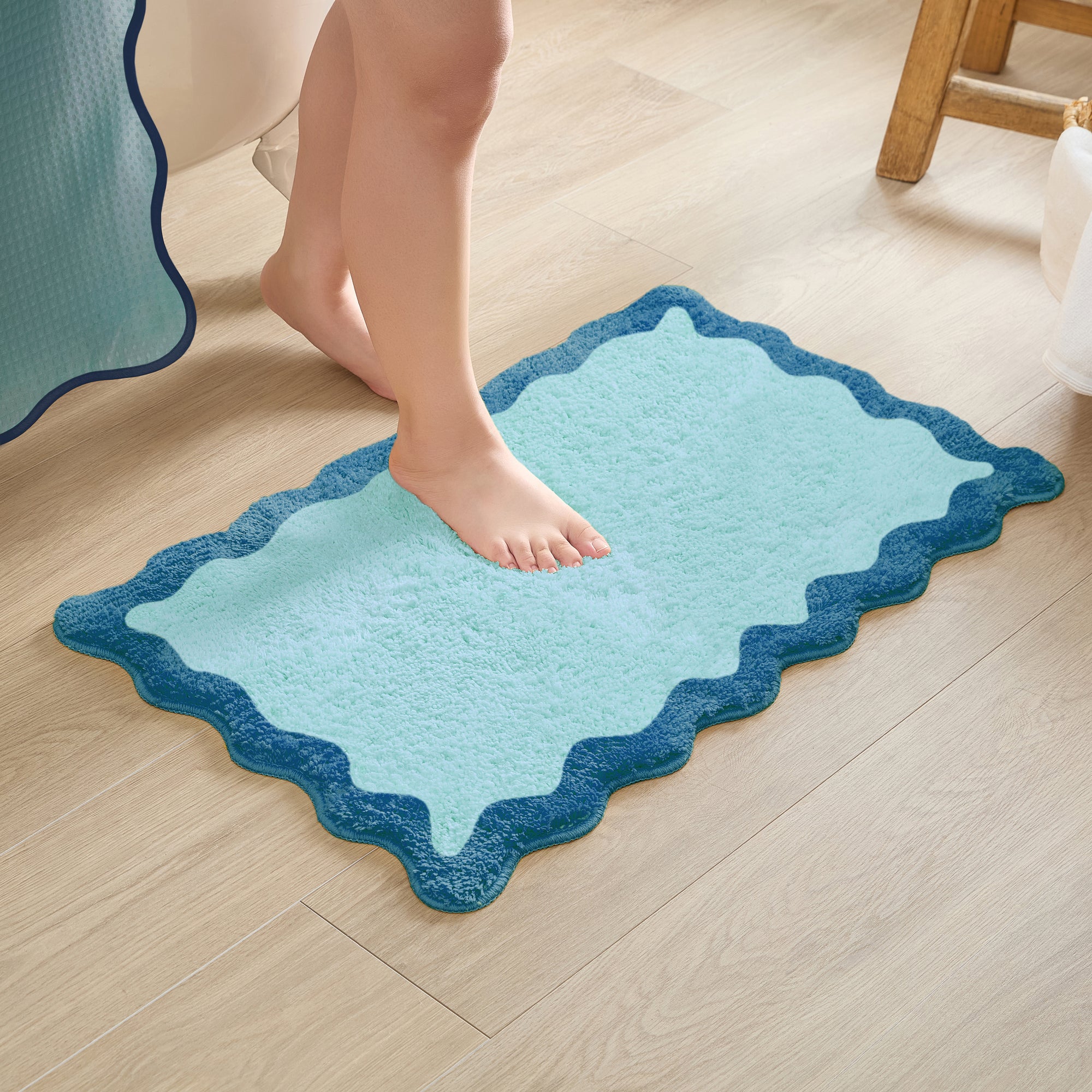 Person stepping onto a blue bath mat on a wooden floor