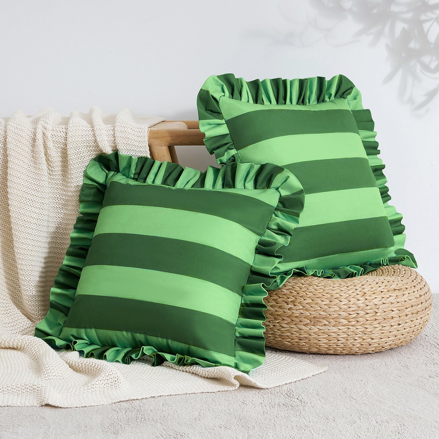 Two green striped pillows with ruffled edges on a neutral background