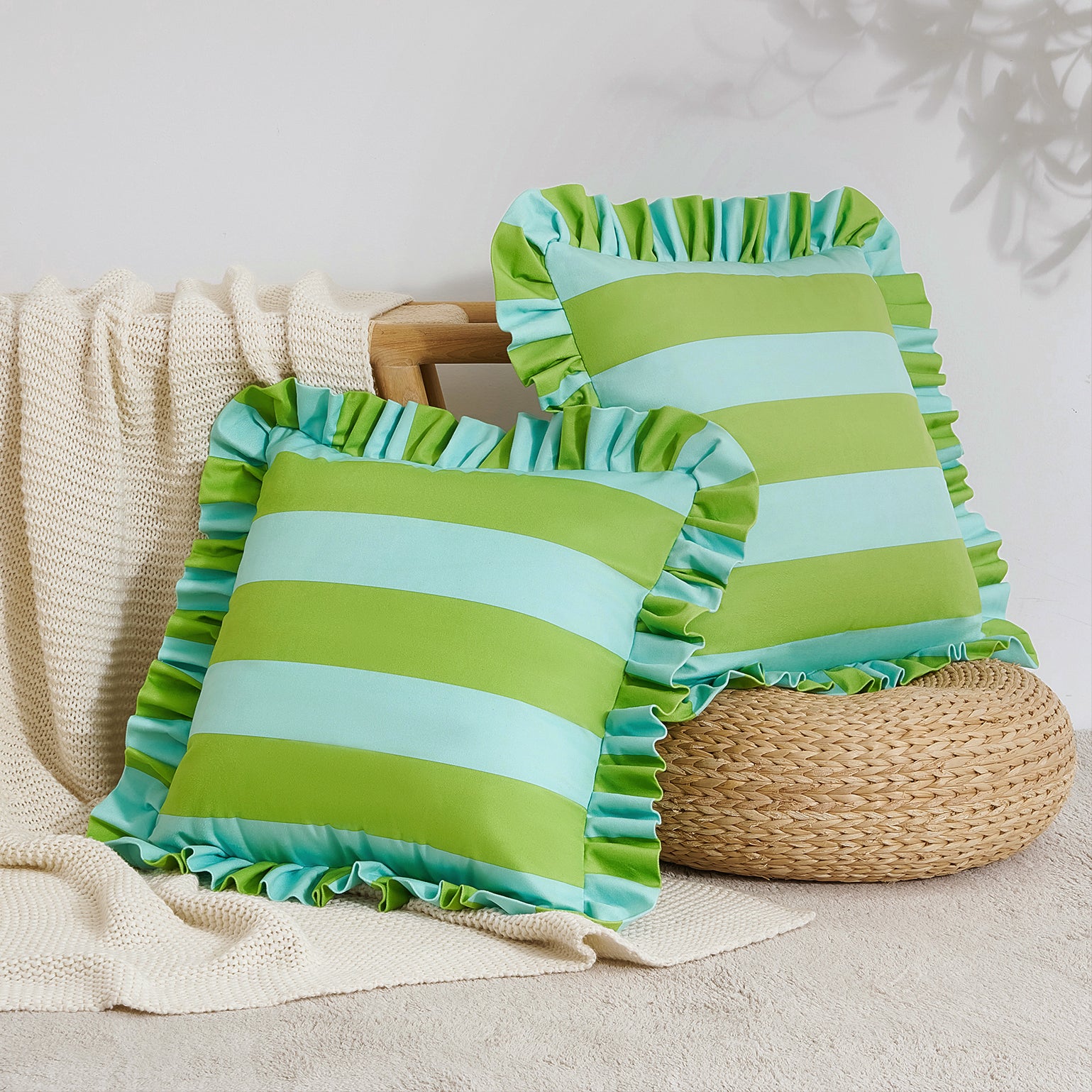 Two green and blue striped pillows with ruffled edges on a neutral background.