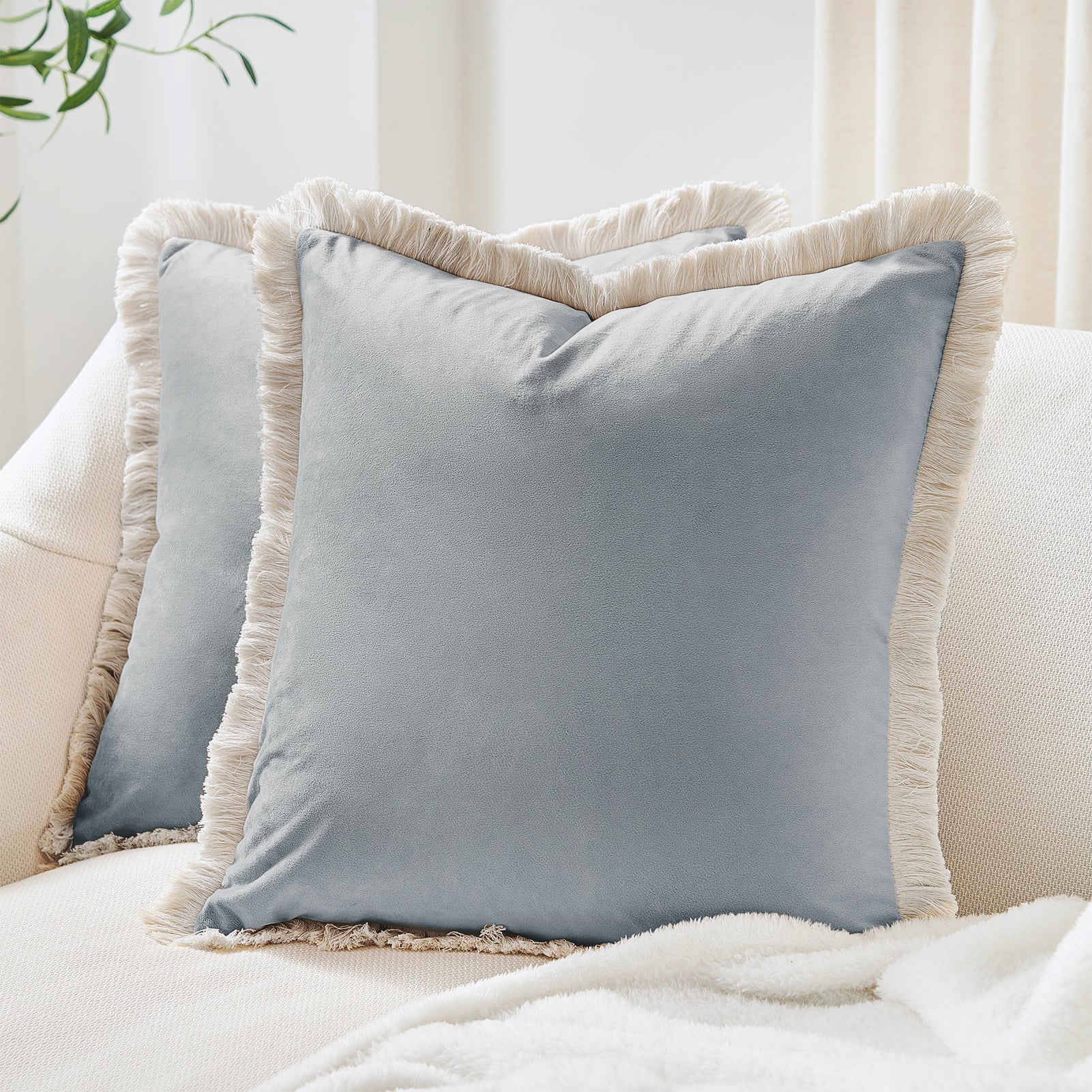 Gray pillows with beige fringes on a light-colored sofa