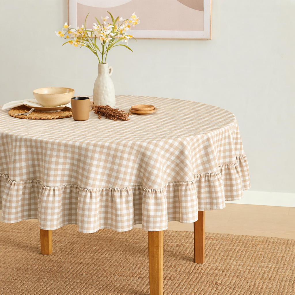 Round table with a checkered tablecloth, vase with flowers, and decorative items in a room.