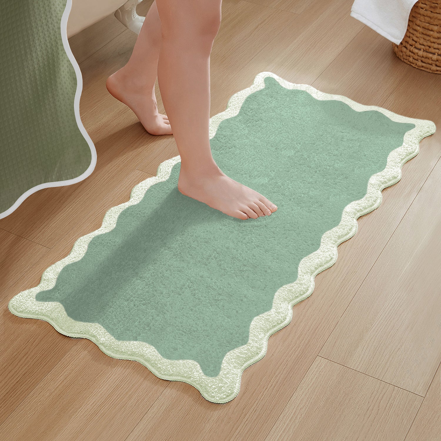 Green bath mat with scalloped edge on a wooden floor