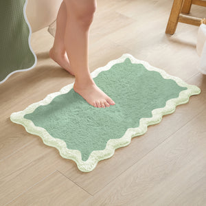 Green bath mat on a wooden floor with a person stepping onto it.