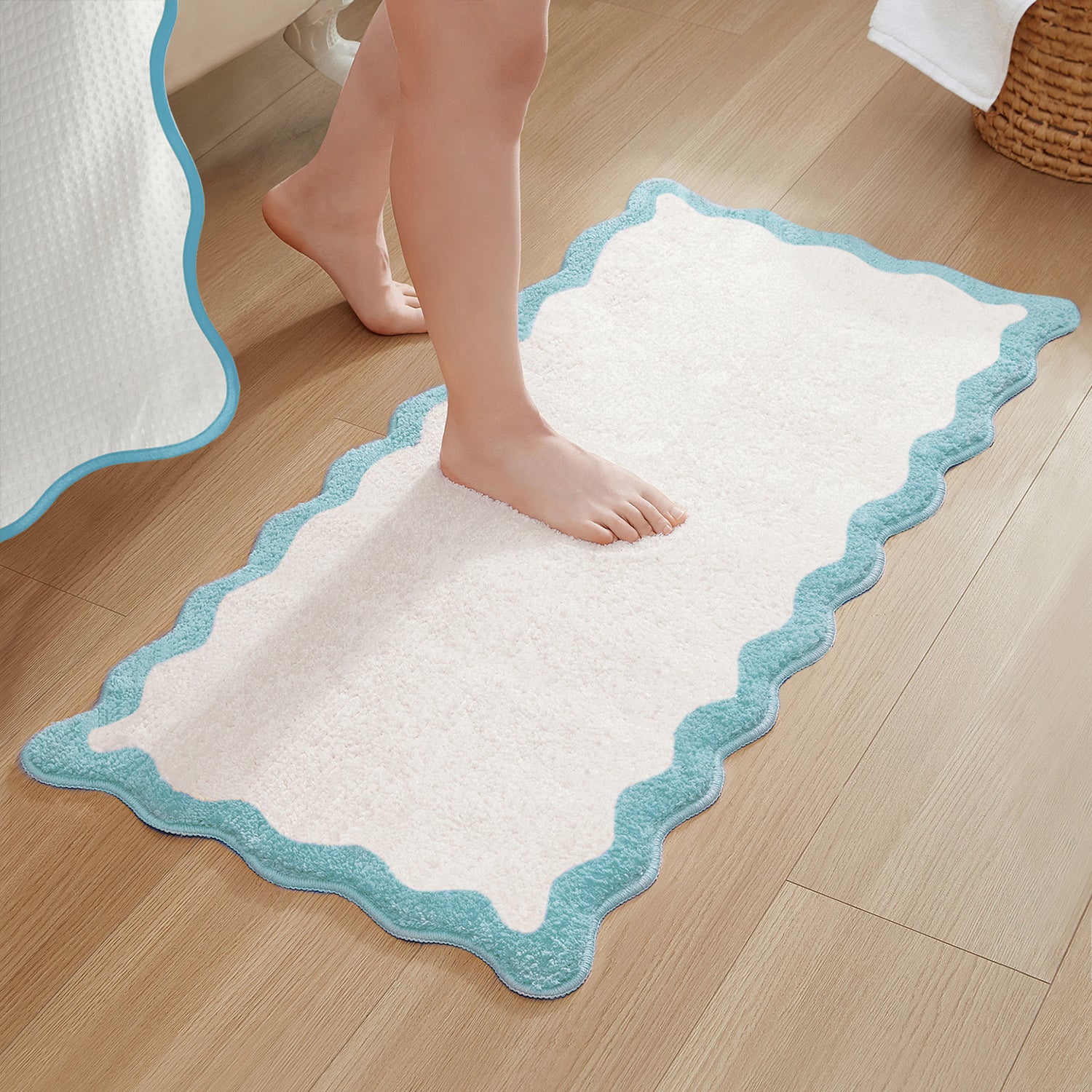 White bath mat with blue border on a wooden floor, person stepping onto it.
