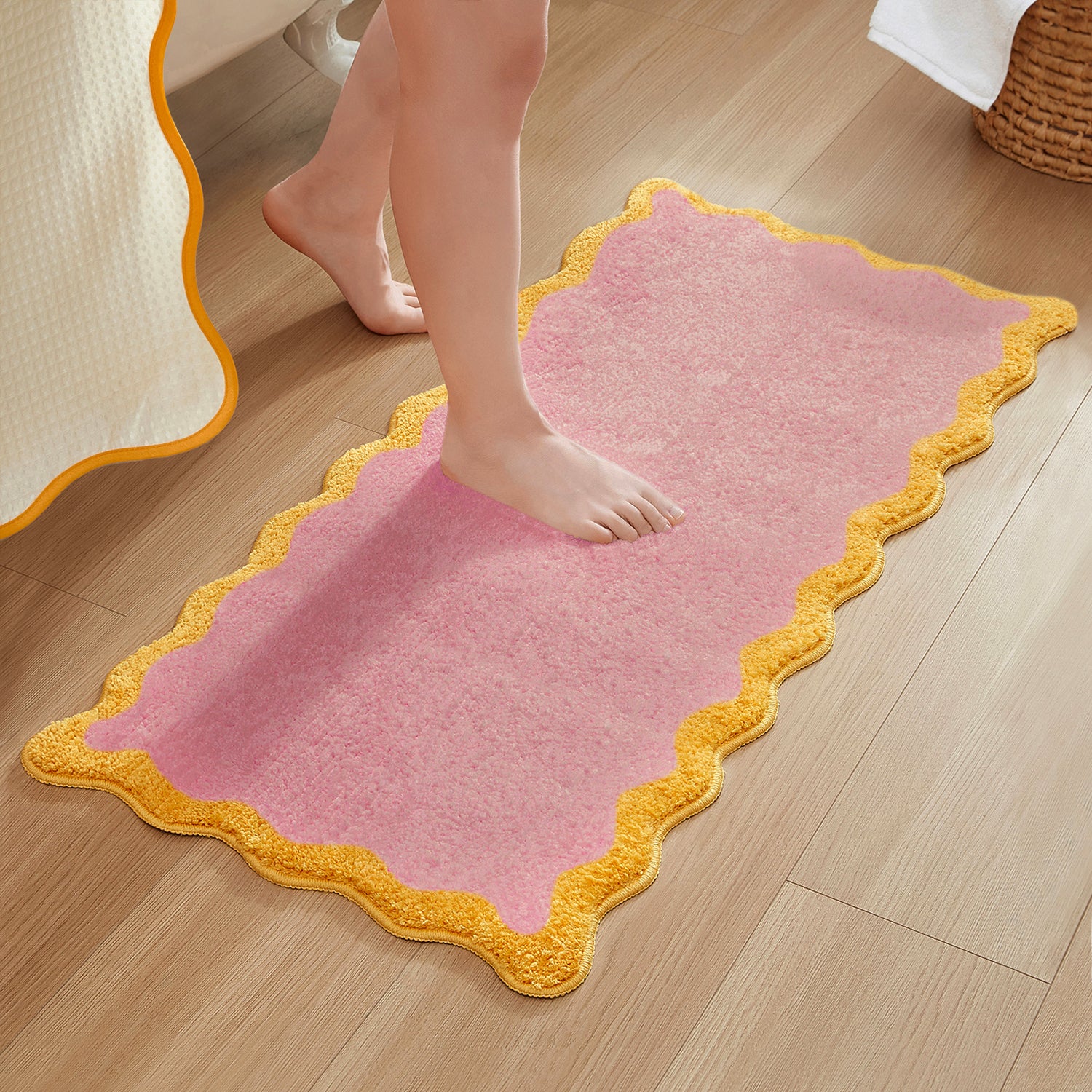 Pink bath mat with yellow border on a wooden floor