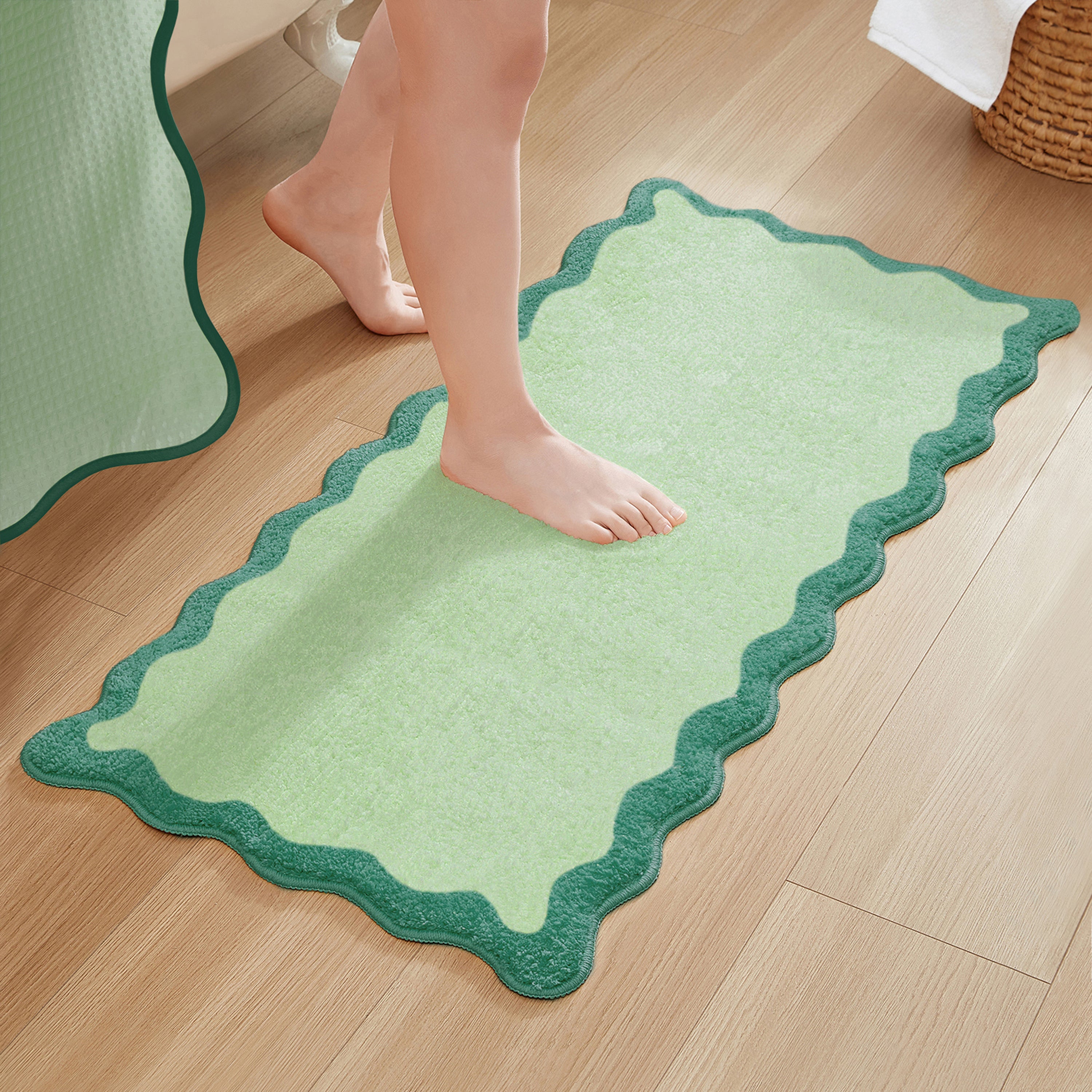 Green bath mat with scalloped edge on a wooden floor