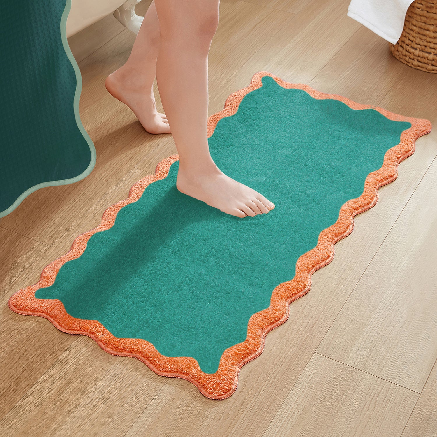 Green bath mat with orange border on a wooden floor