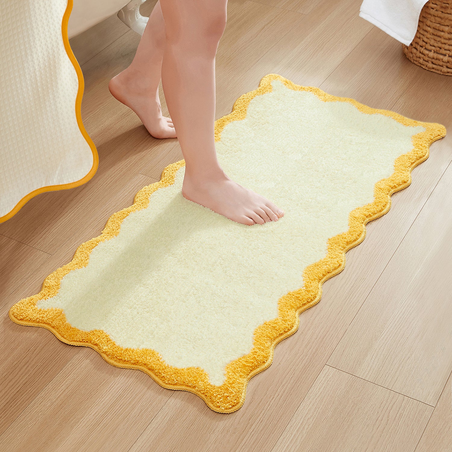 Light green bath mat with yellow border on a wooden floor