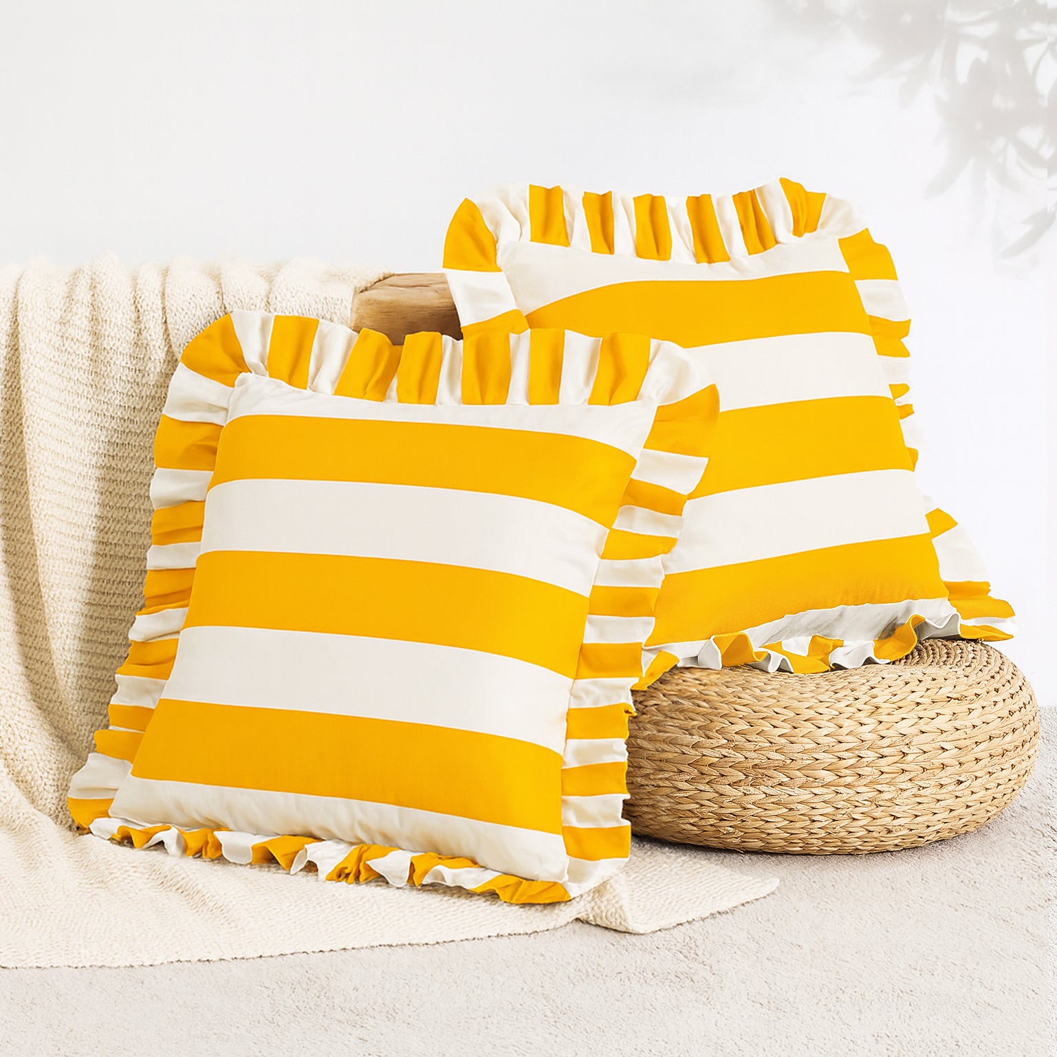 Yellow and white striped pillows with ruffle edges on a neutral background