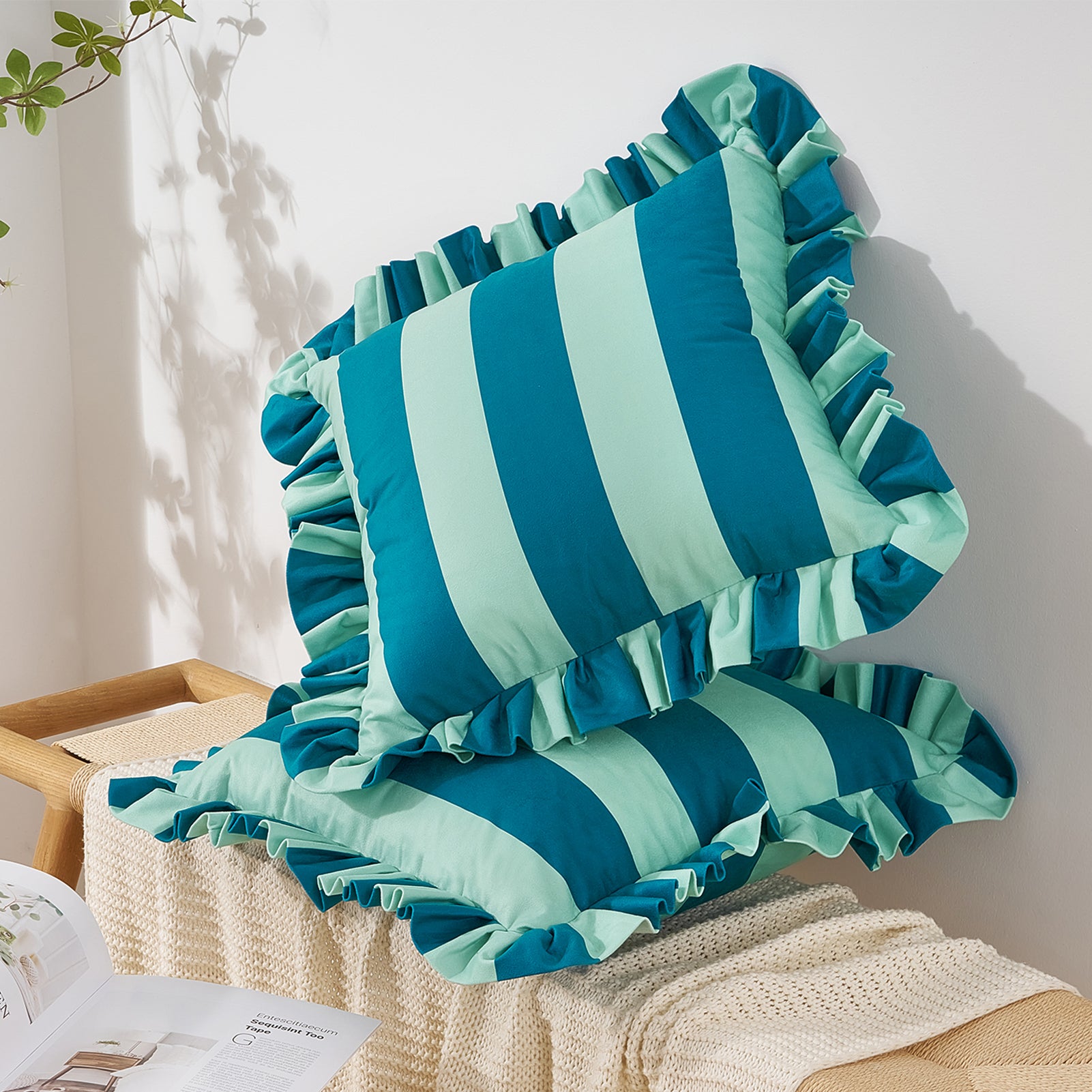 Teal and green striped pillows with ruffles on a beige surface.