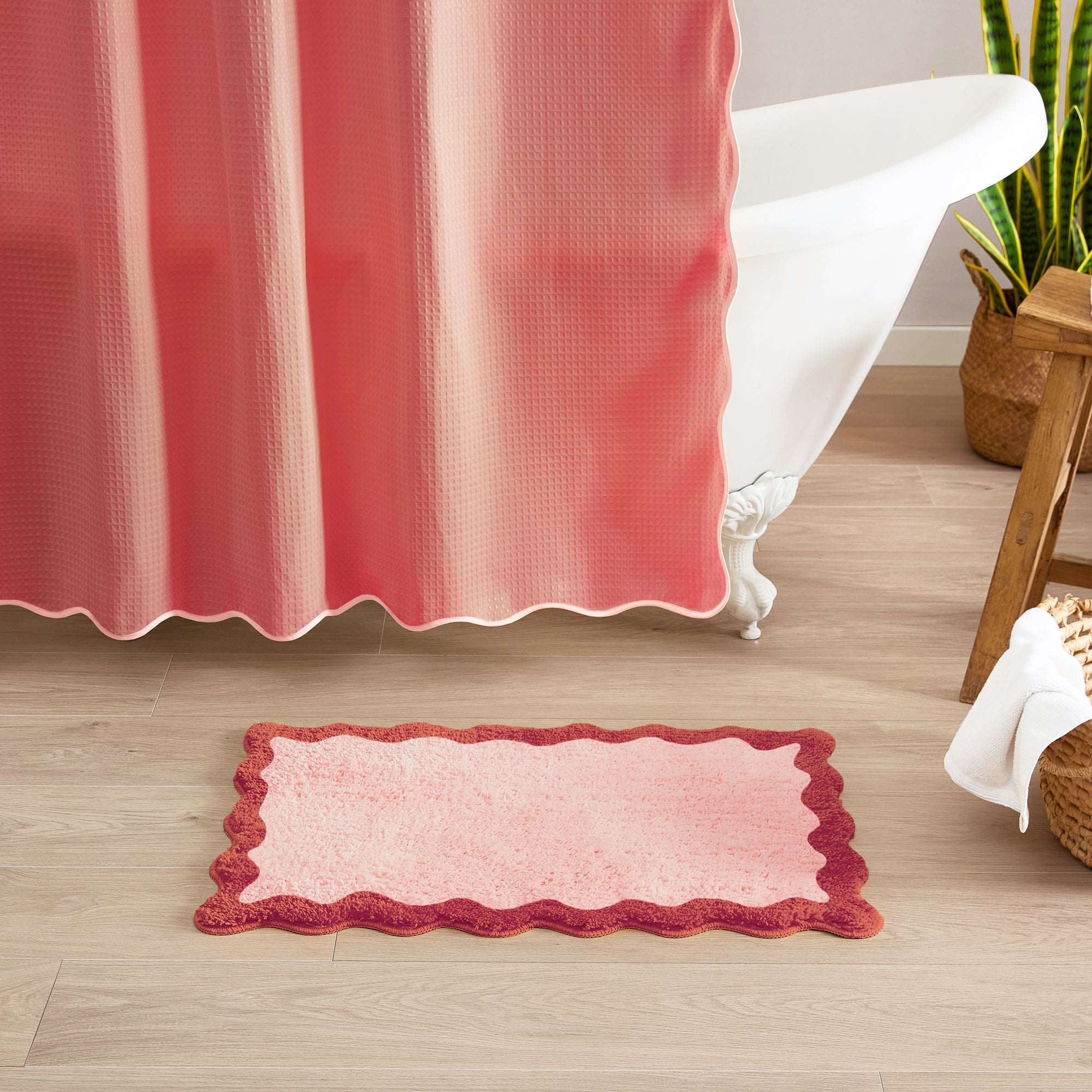 Bathroom with a red and white shower curtain and matching bath mat on a wooden floor.
