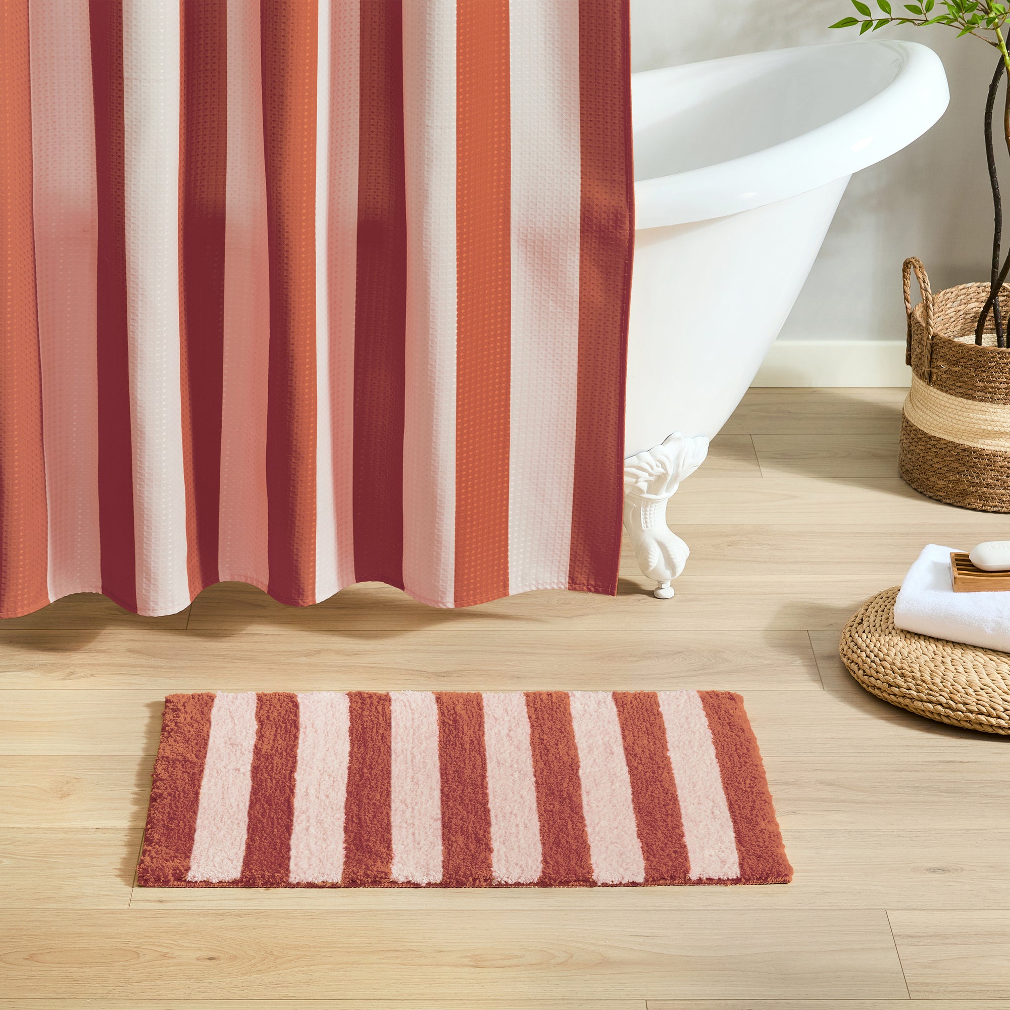 Striped red and white shower curtain with matching bath mat on wooden floor
