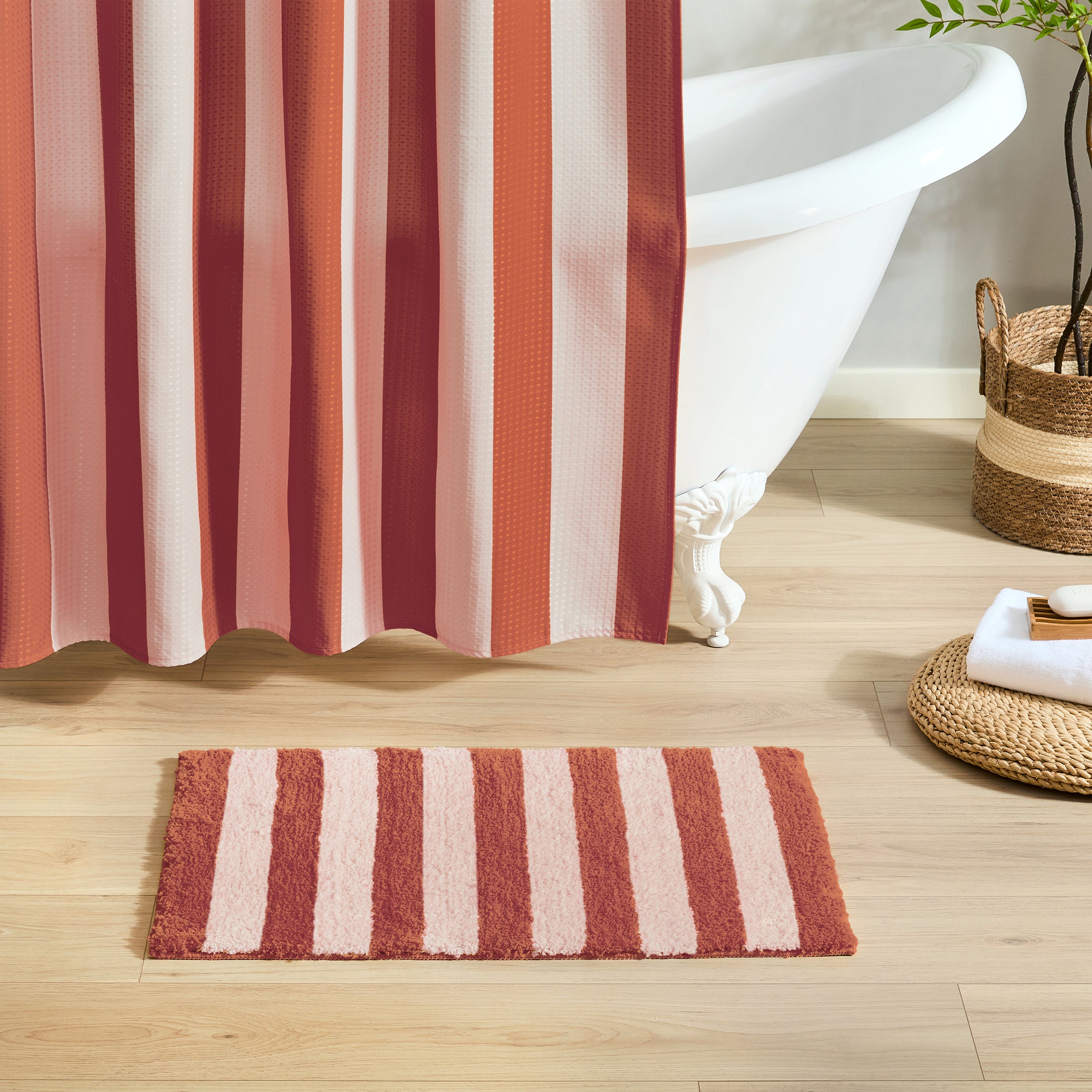 Striped red and white shower curtain with matching bath mat on wooden floor
