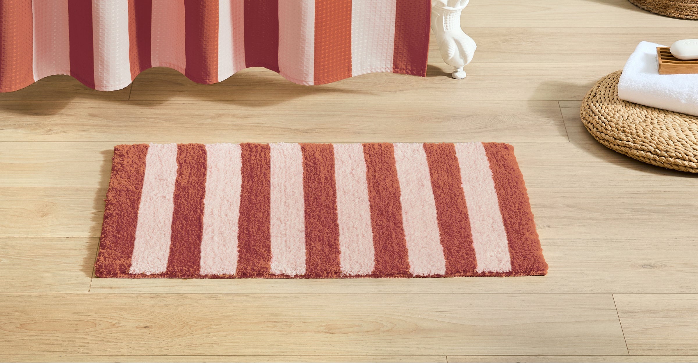 Striped red and white shower curtain with matching bath mat on wooden floor