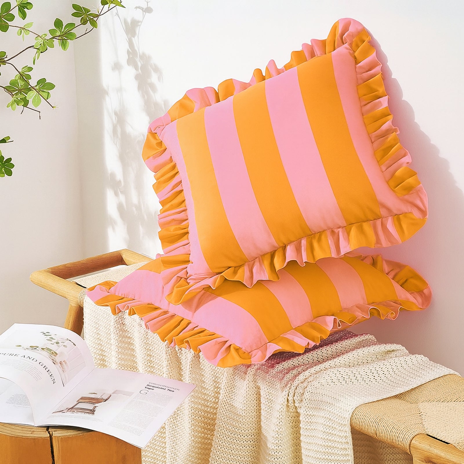 Pink and orange striped cushions with ruffled edges on a wooden chair against a white wall.