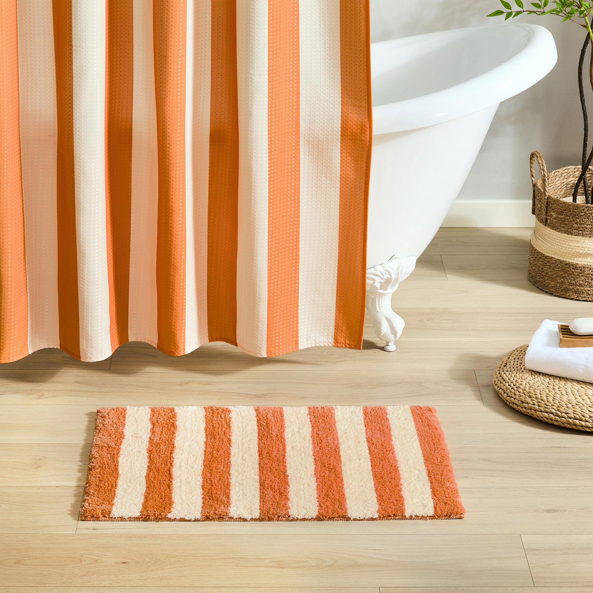 Bathroom with striped shower curtain and bath mat on wooden floor