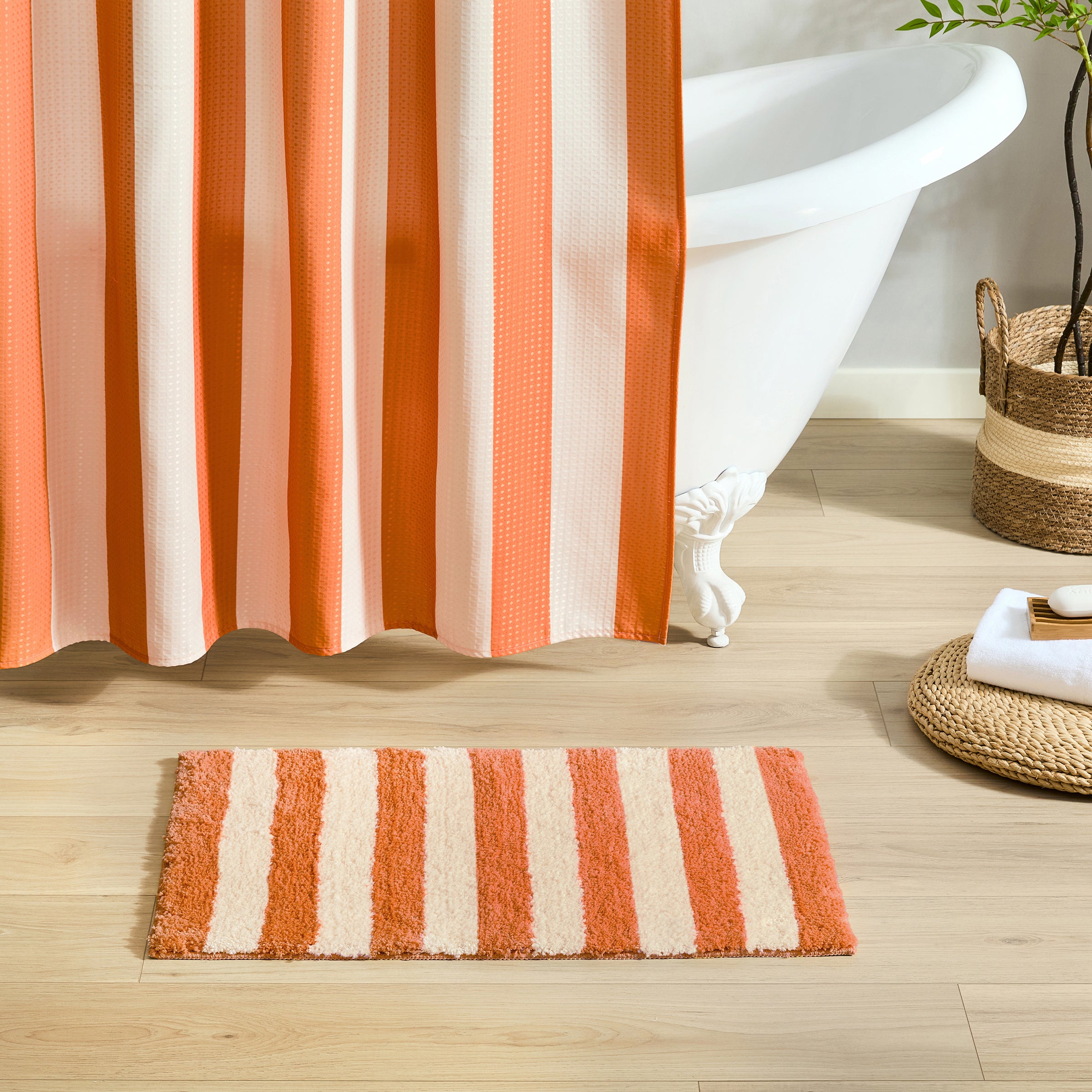 Bathroom with striped shower curtain and bath mat on wooden floor