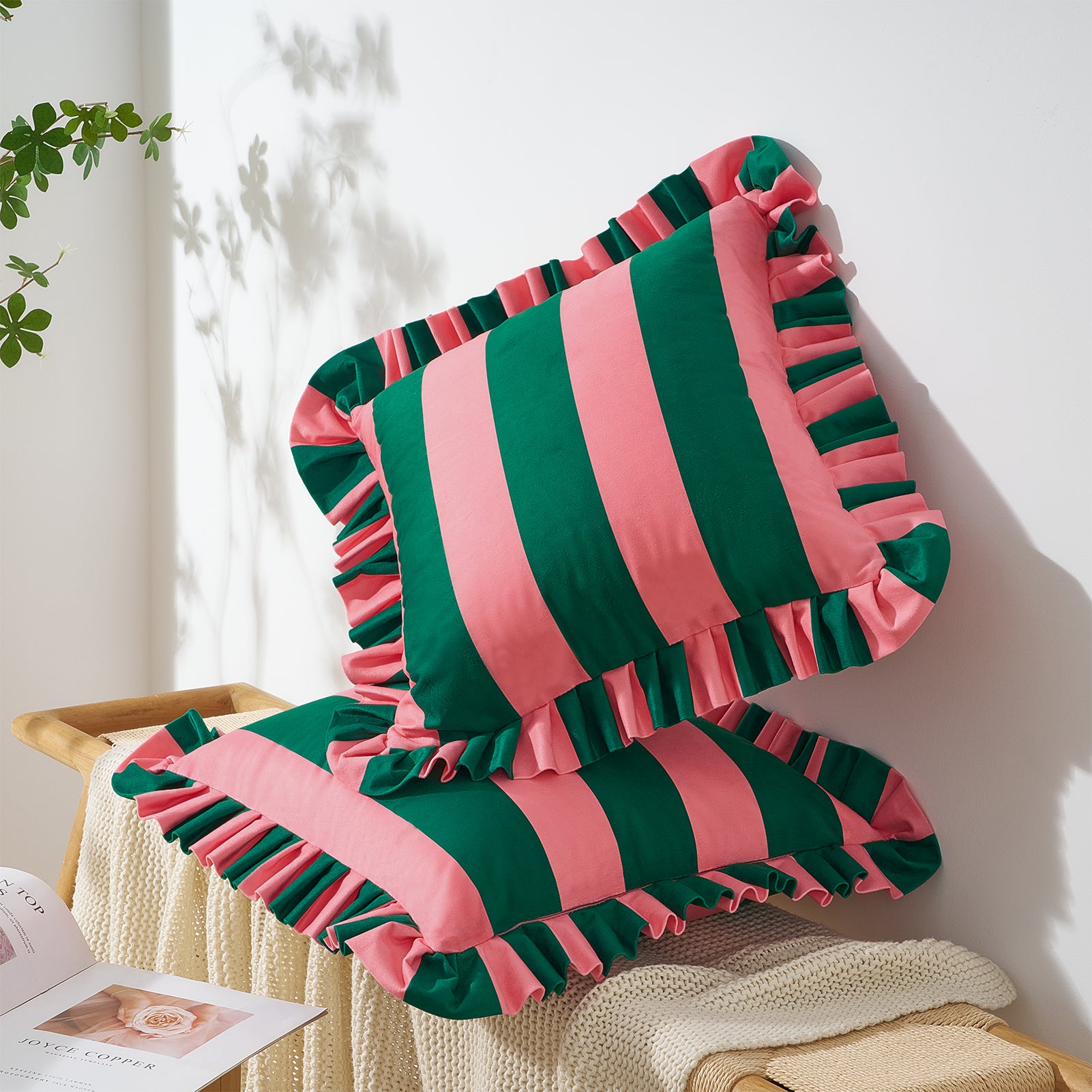 Pink and green striped pillow with ruffles on a wooden surface.