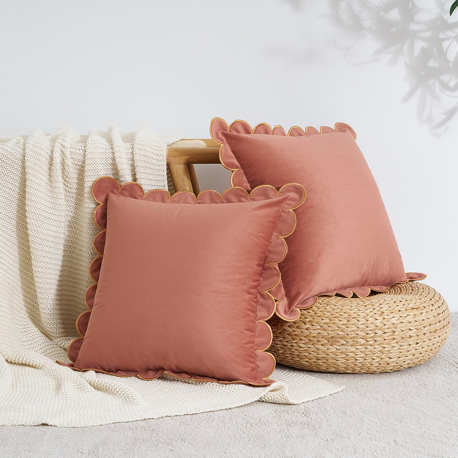 Two pink pillows with scalloped edges on a textured surface.