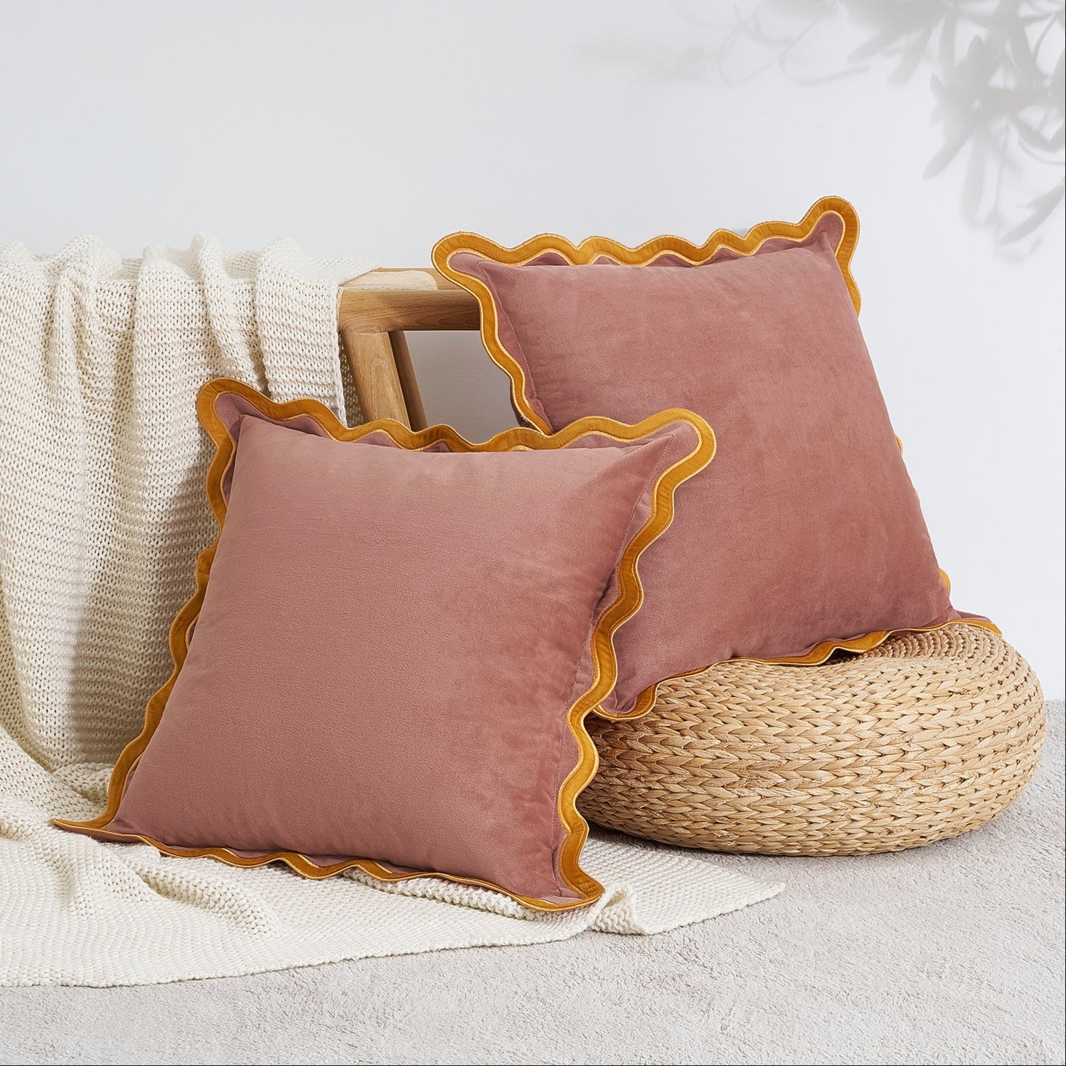 Two pink pillows with scalloped edges on a textured surface.