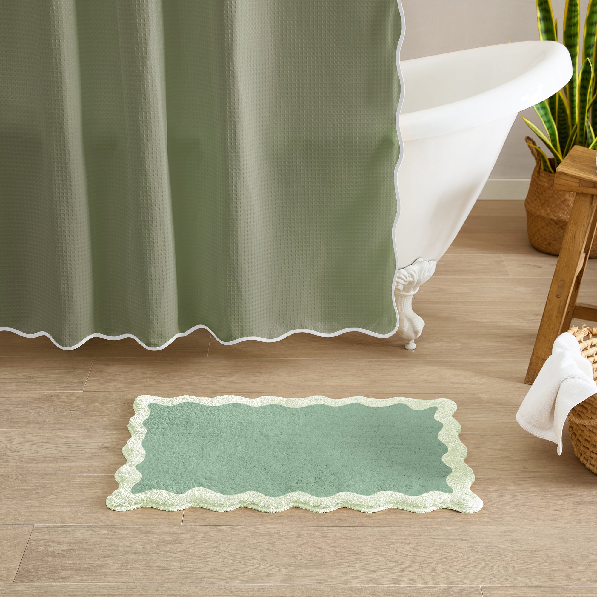 Green bath mat on a wooden floor with a green shower curtain in the background.