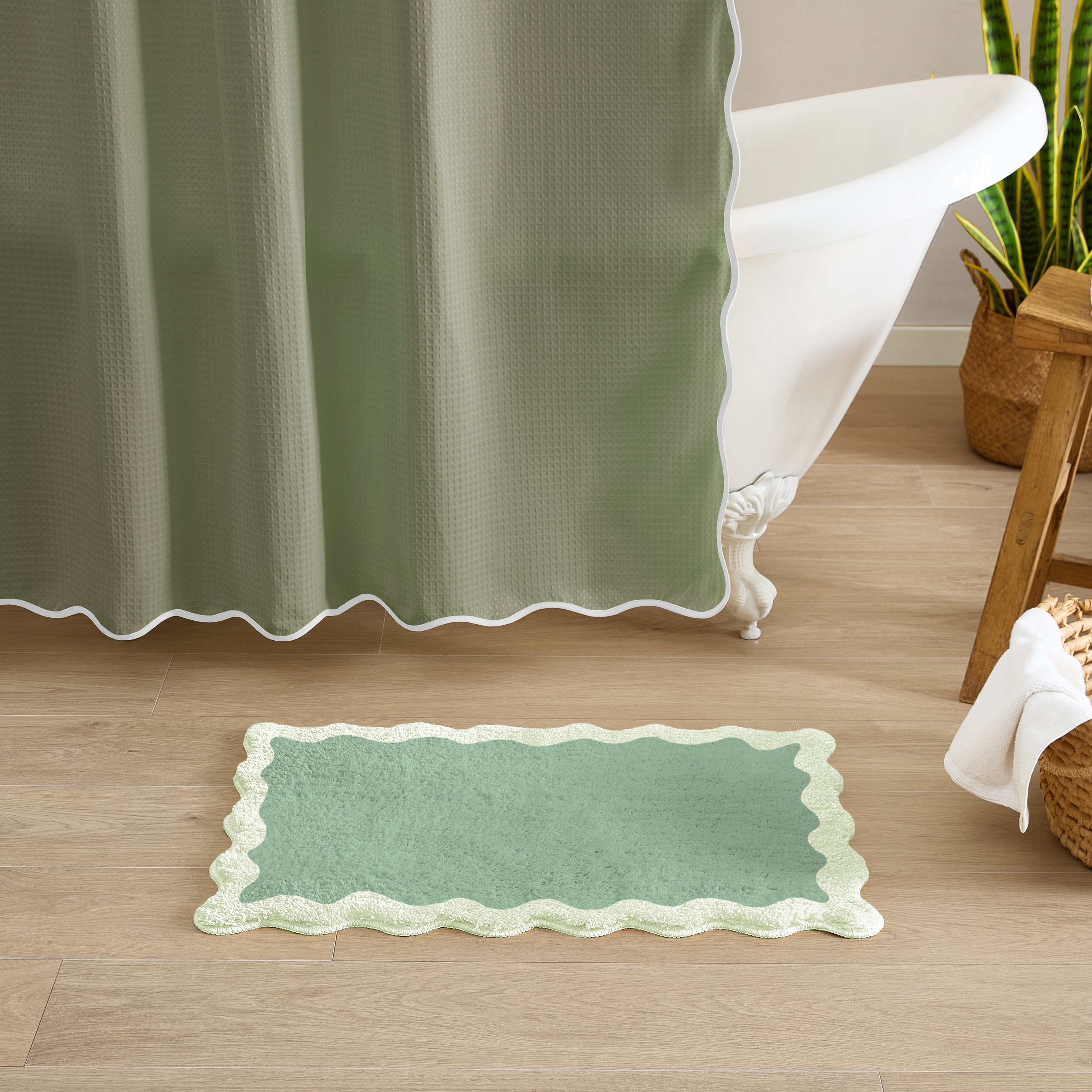Green bath mat on a wooden floor with a green shower curtain in the background.